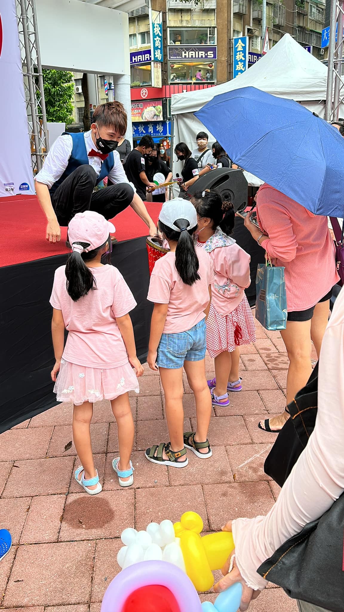 演出後柯男蹲在舞台邊,和穿粉紅衣服的小女孩們互動