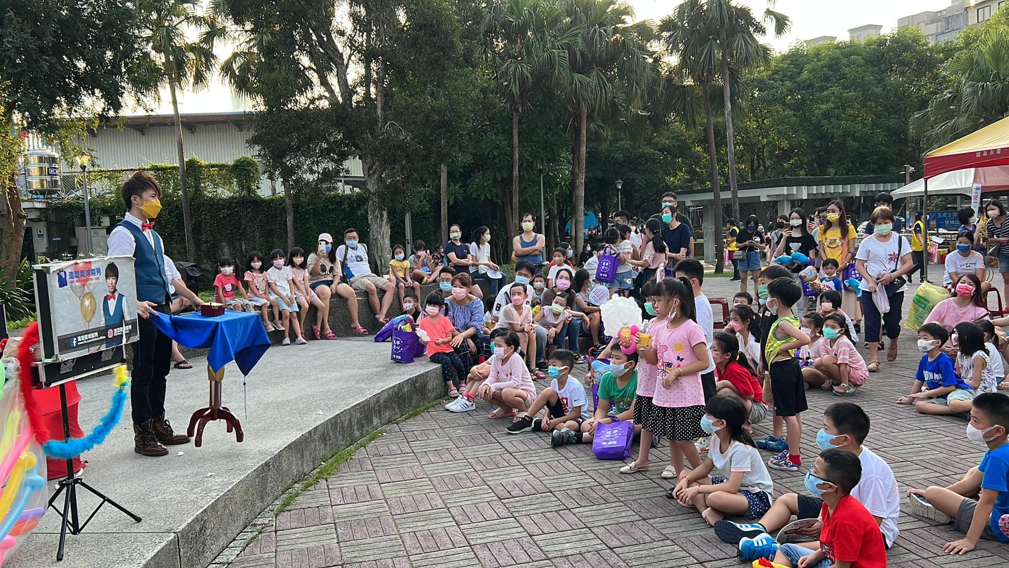 南港玉成公園戶外舞台，柯男表演魔術，台階上坐滿孩子與家長
