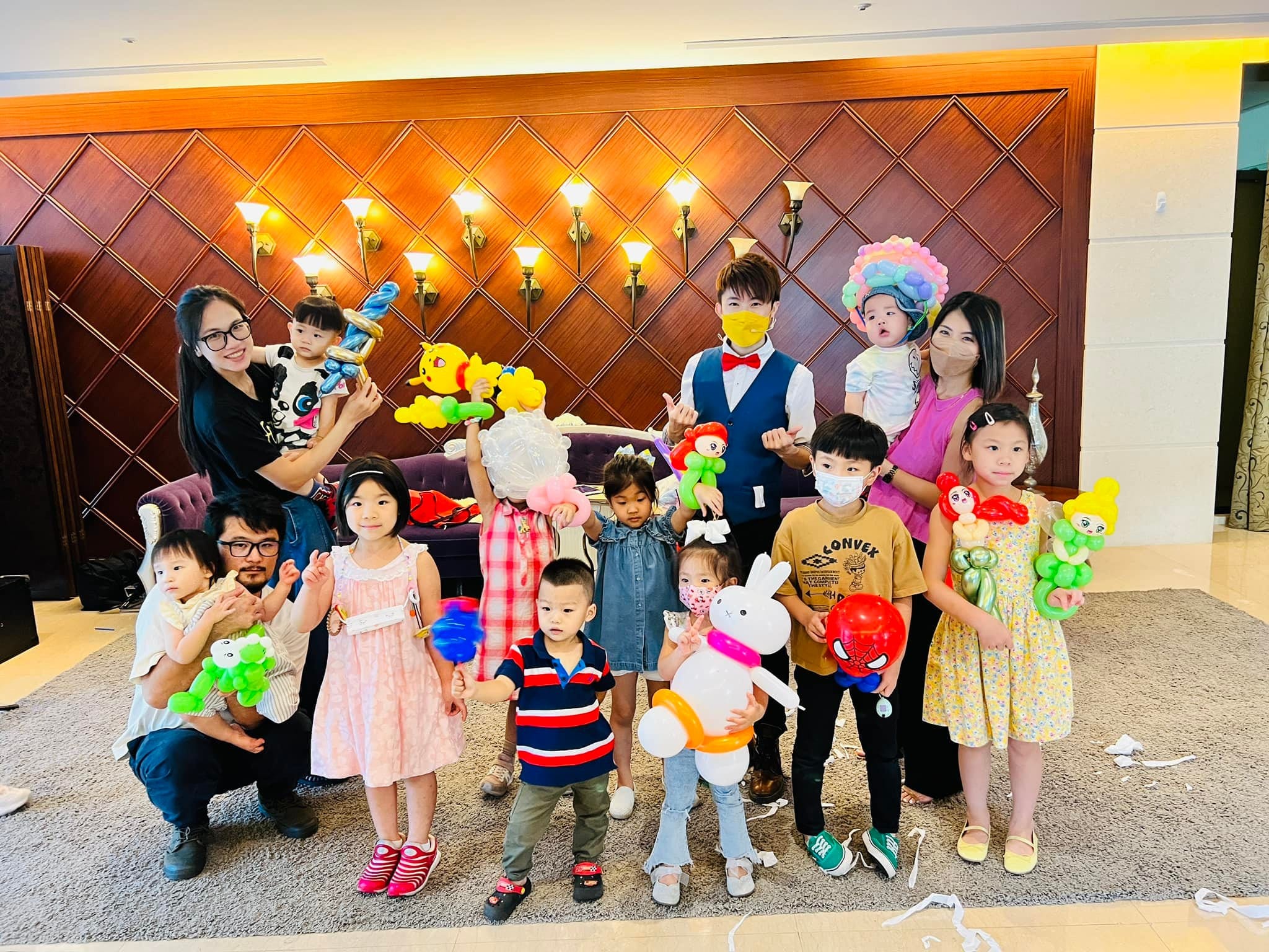 生日派對上，孩子們拿著兔子、蜘蛛人、娃娃等造型氣球與柯男合照