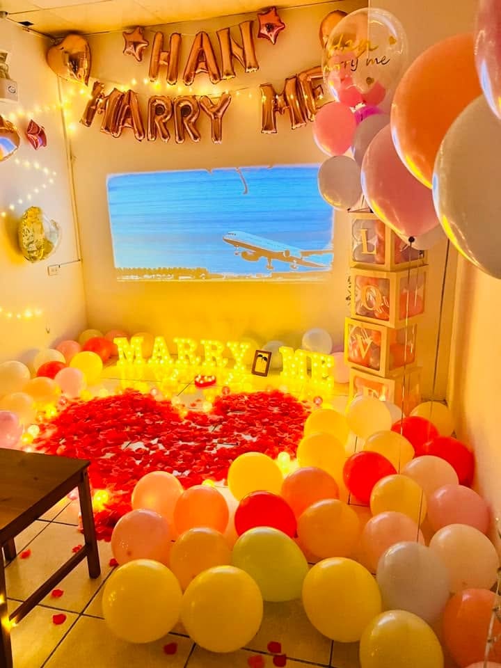 求婚房間裡的 MARRY ME 燈字、紅色玫瑰花瓣愛心與彩色氣球