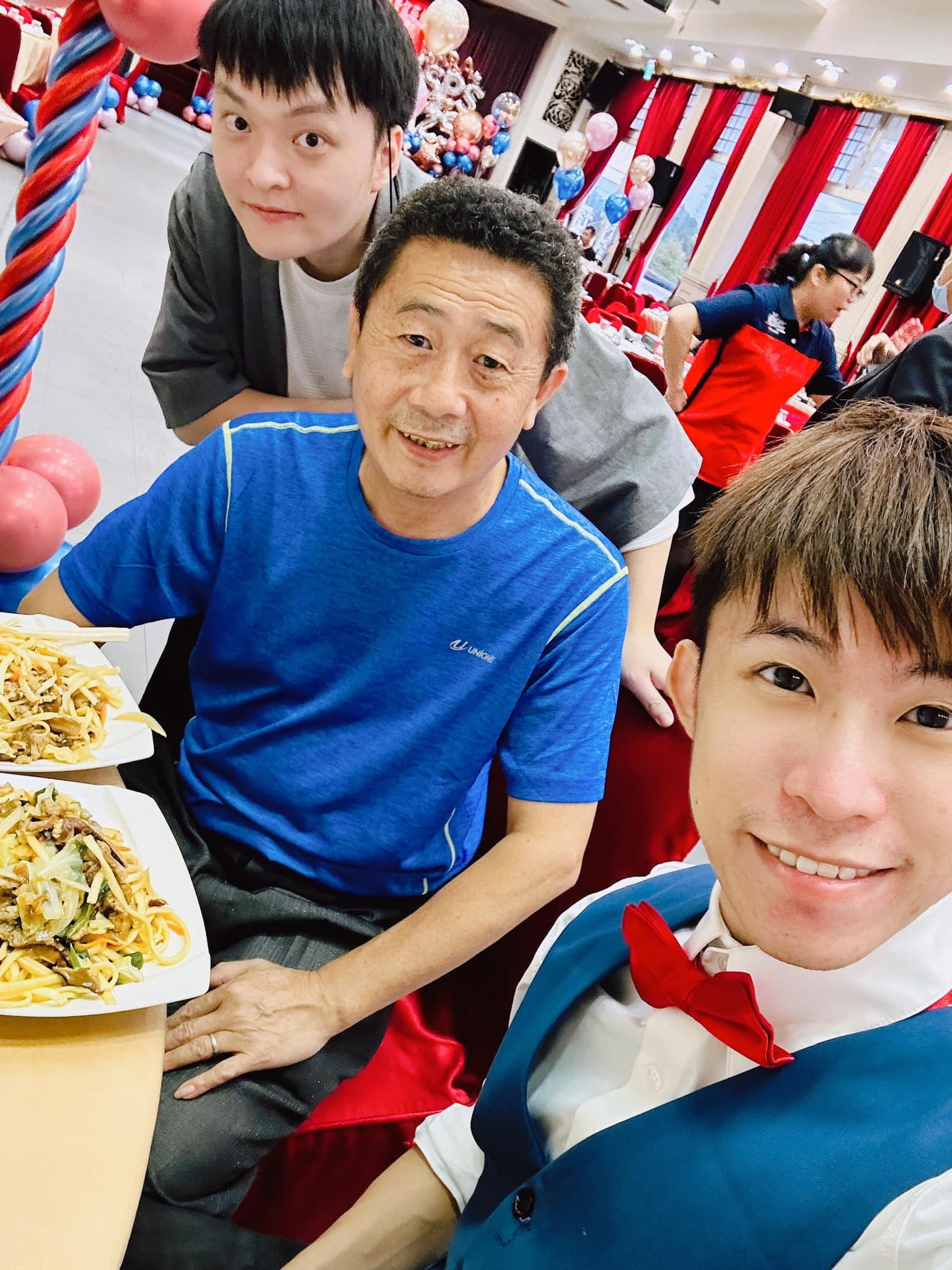 柯男在餐會圓桌旁與柯爹自拍，桌上擺著炒麵