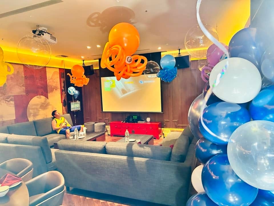 橘色大章魚氣球吊在投影幕前方，旁邊是透明泡泡球與藍色小章魚