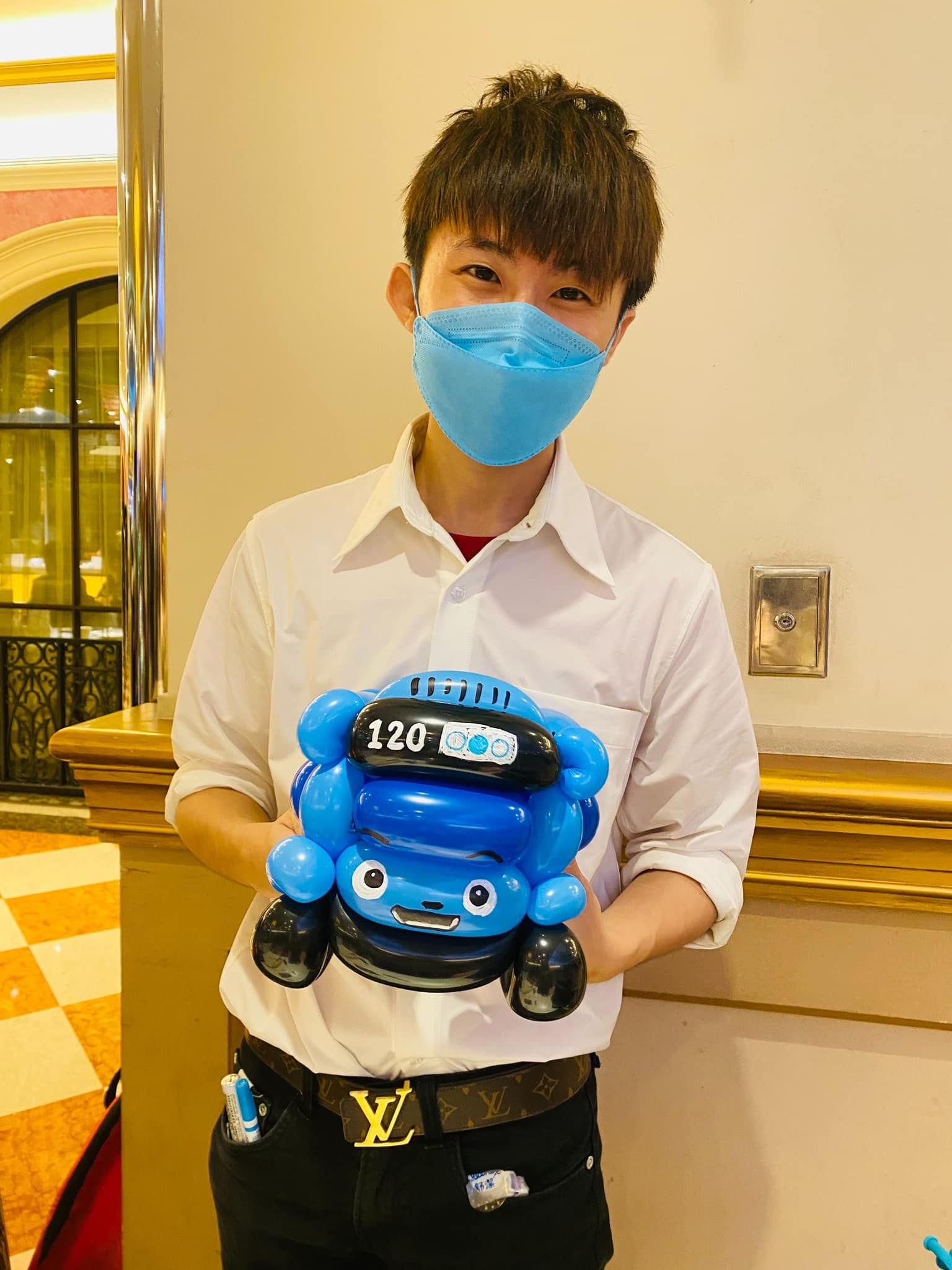 柯男拿著車頭寫 120 的藍色 TAYO 小巴士造型氣球