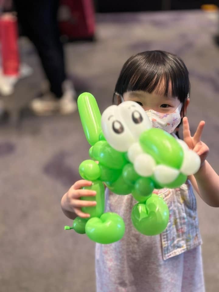 小女孩抱著綠色大眼睛造型氣球比 YA