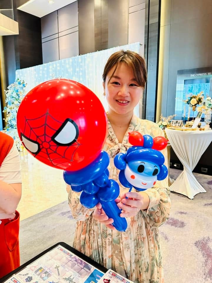 女賓客拿著紅色蜘蛛人頭手持氣球和藍色小人造型氣球