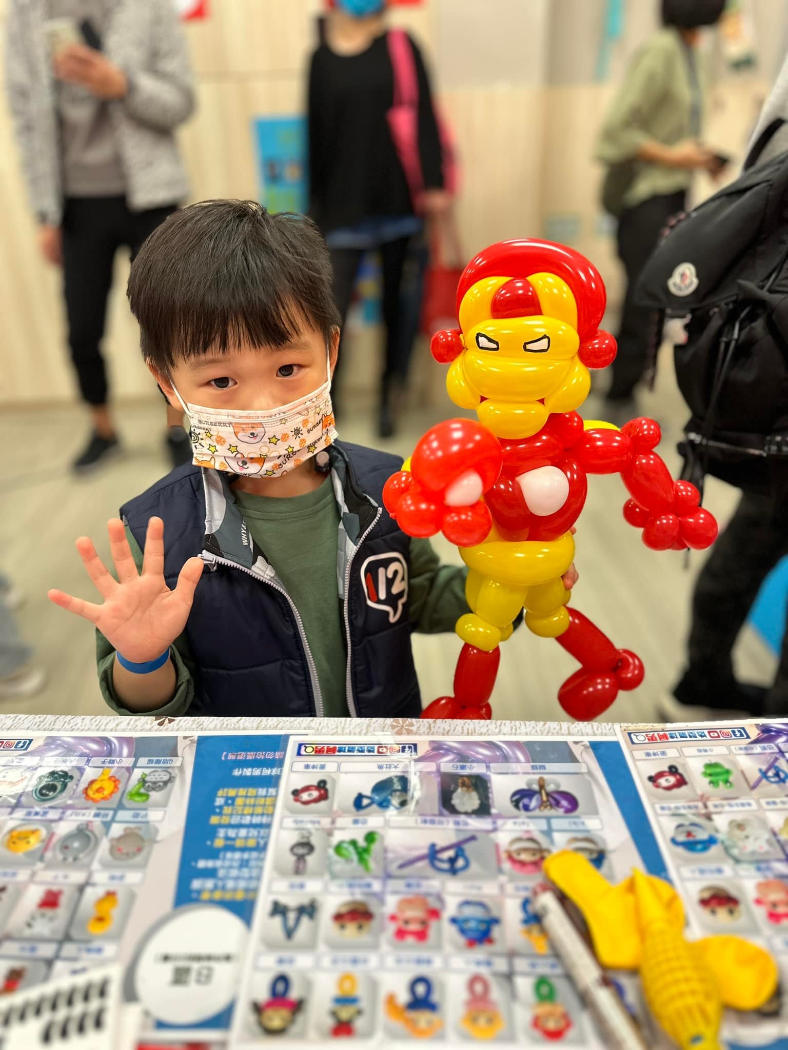 小男孩揮手，身旁是和他差不多高的鋼鐵人造型氣球