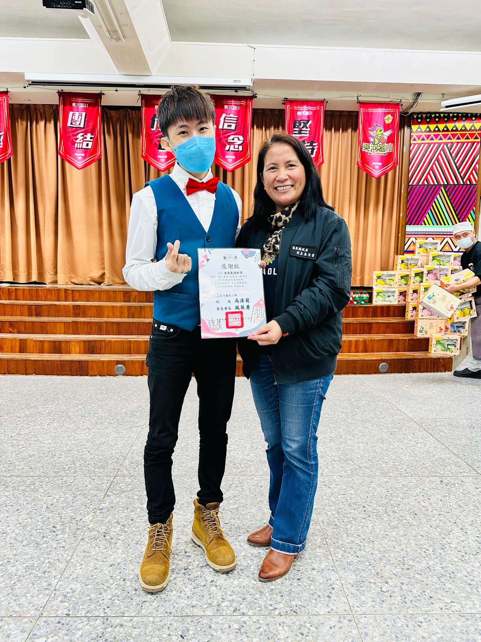 柯男在東河國小禮堂舞台前,與主辦人員一起拿著感謝狀合照