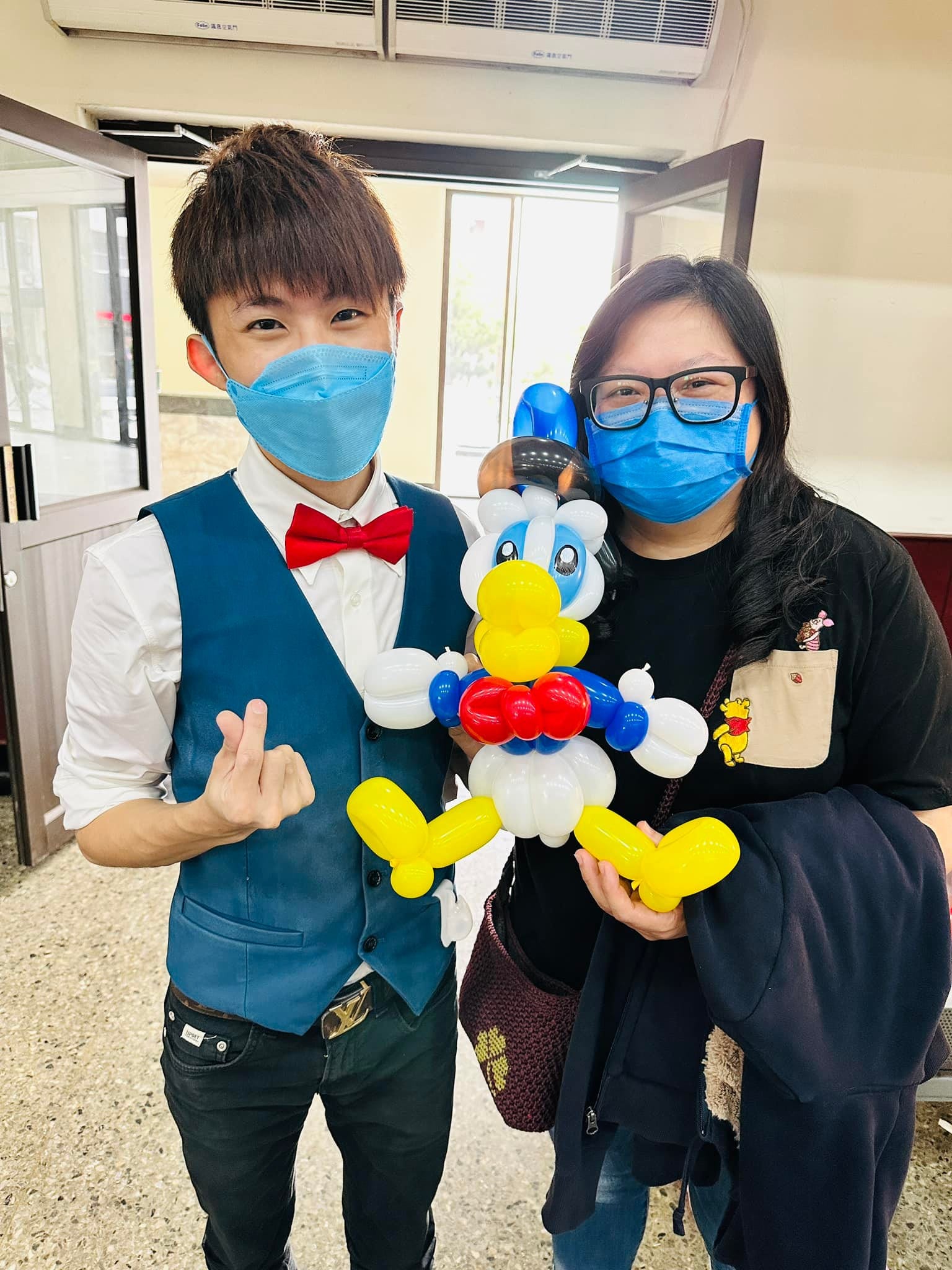 柯男與一位女賓客合照，女賓客抱著藍帽黃嘴的唐老鴨造型氣球