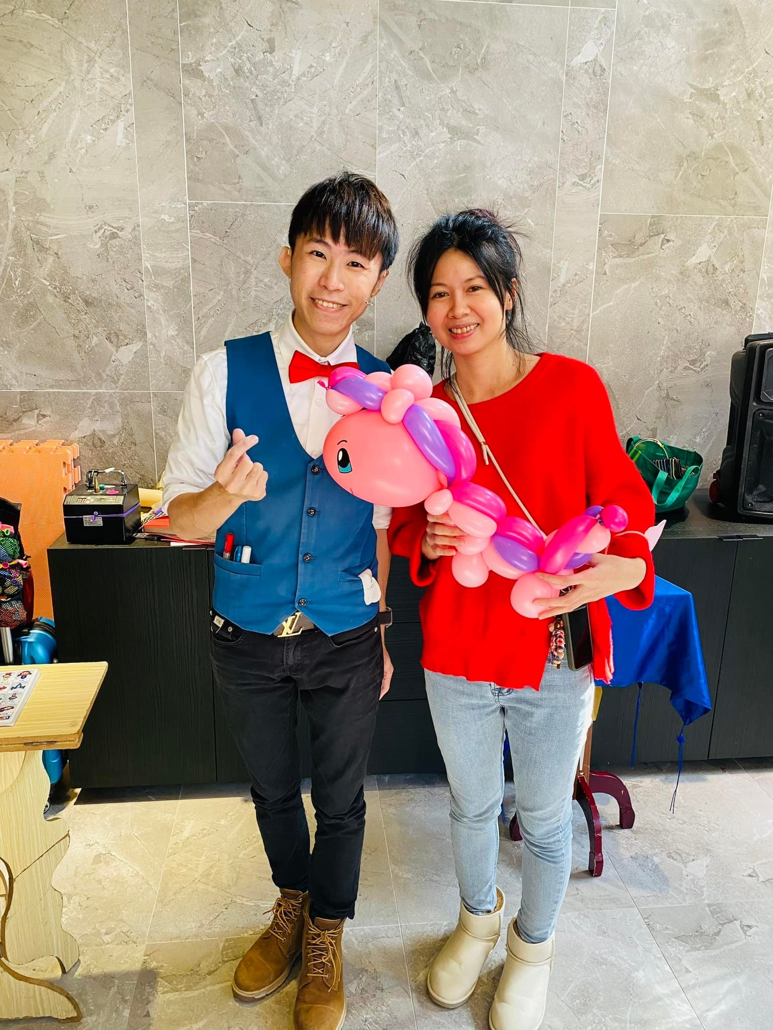 女賓客抱著粉紅色彩虹鬃毛小馬造型氣球，與柯男比心合照