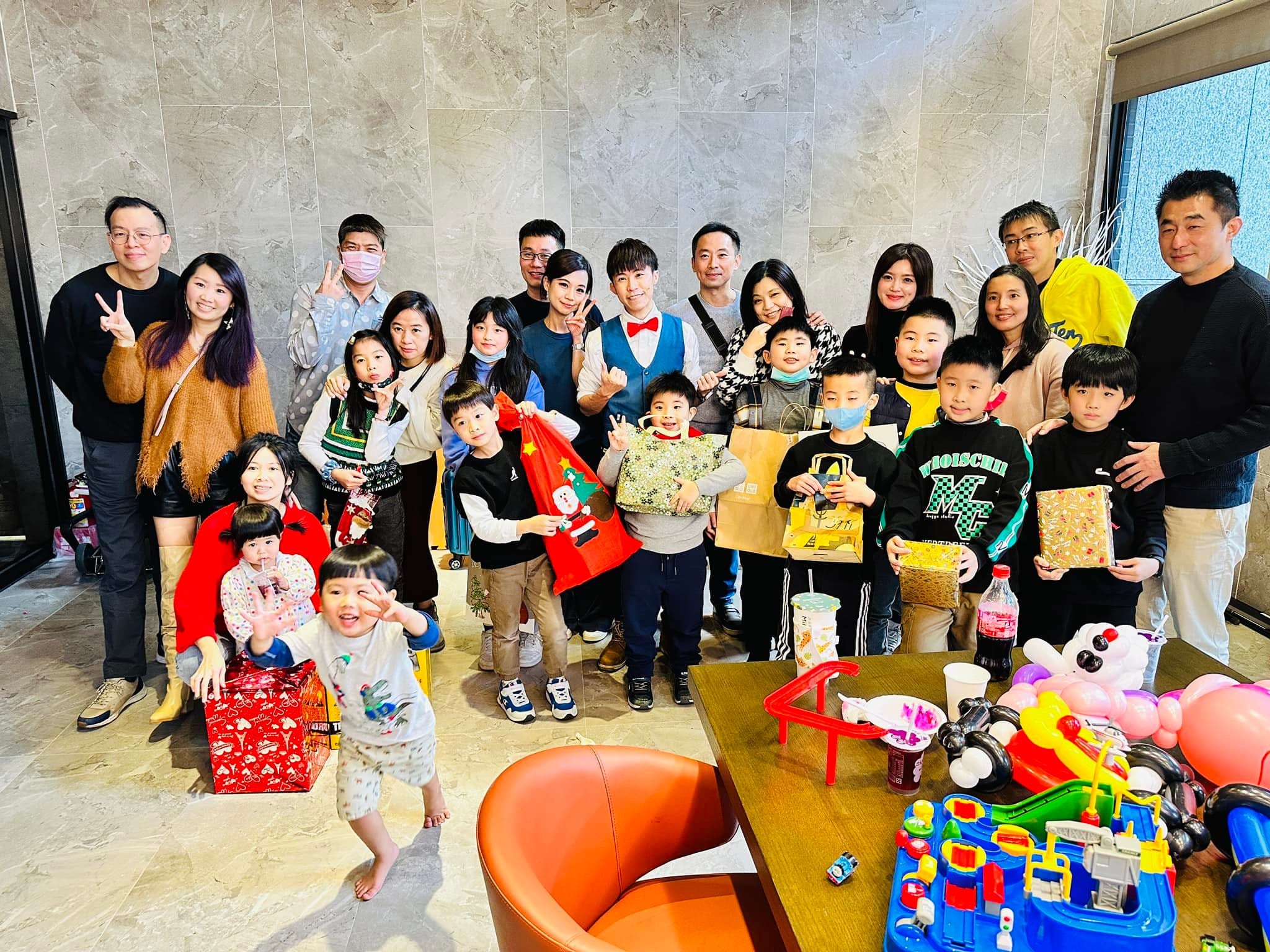 孩子們抱著拆開的聖誕禮物和大人一起大合照