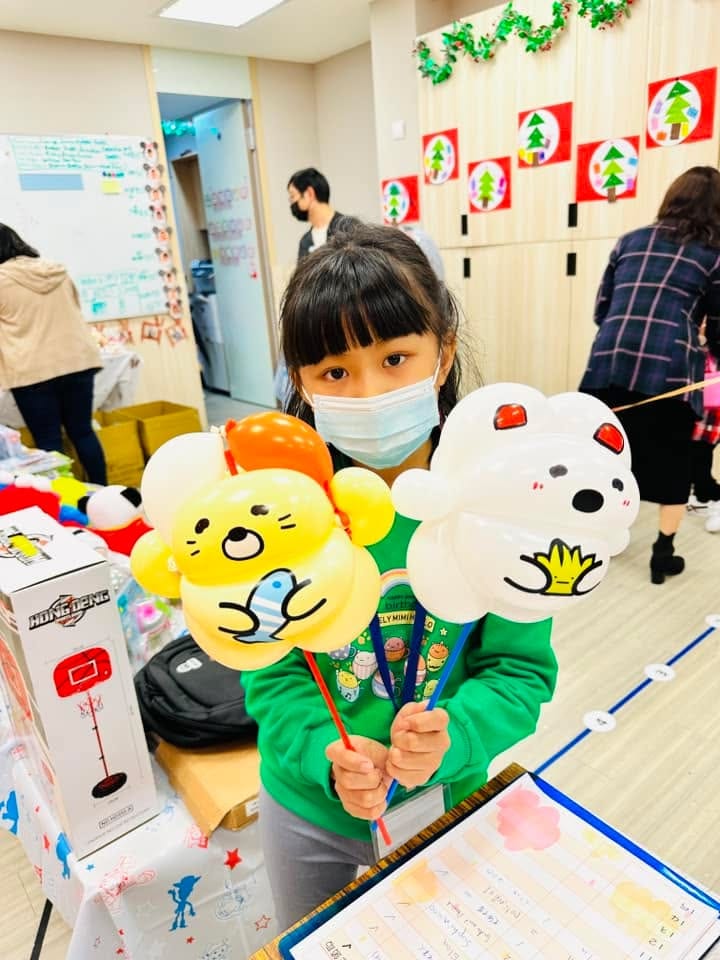 女孩雙手各拿一支黃色小熊與白色小熊造型氣球棒