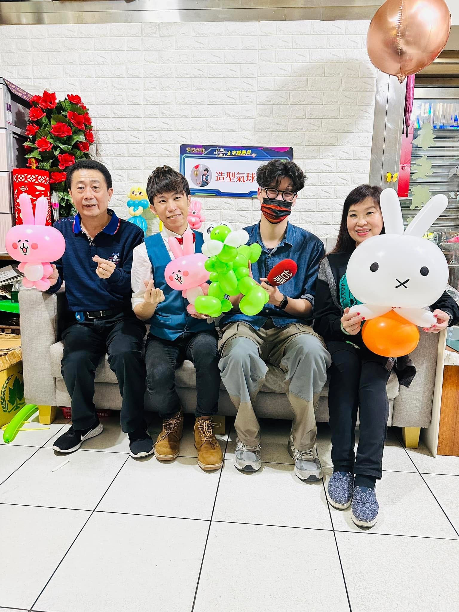 柯男、柯爹、柯媽與記者坐在沙發上，手拿兔子、耀西等造型氣球合照