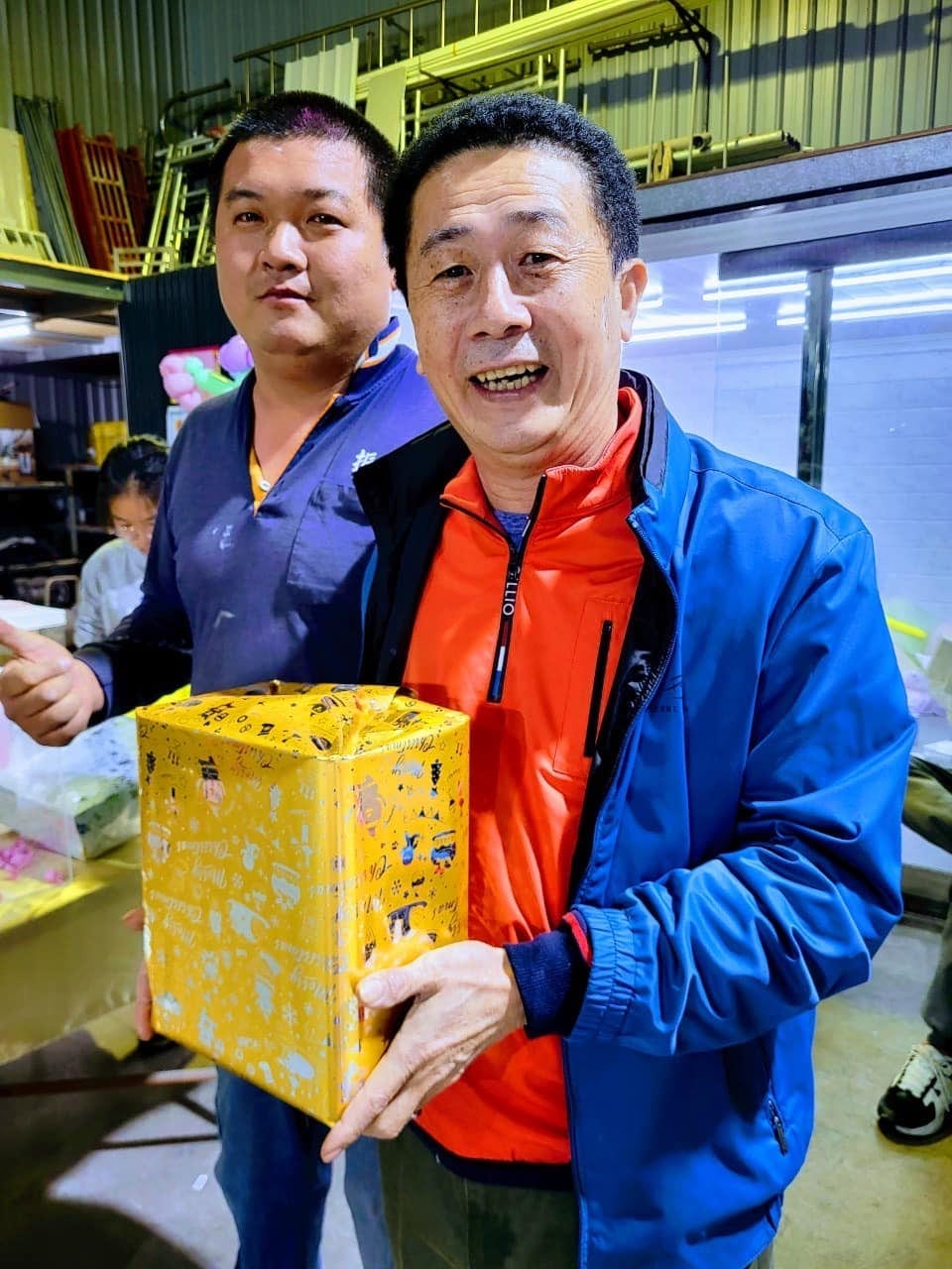 柯爹開心捧著尾牙抽獎抽到的黃色禮物盒