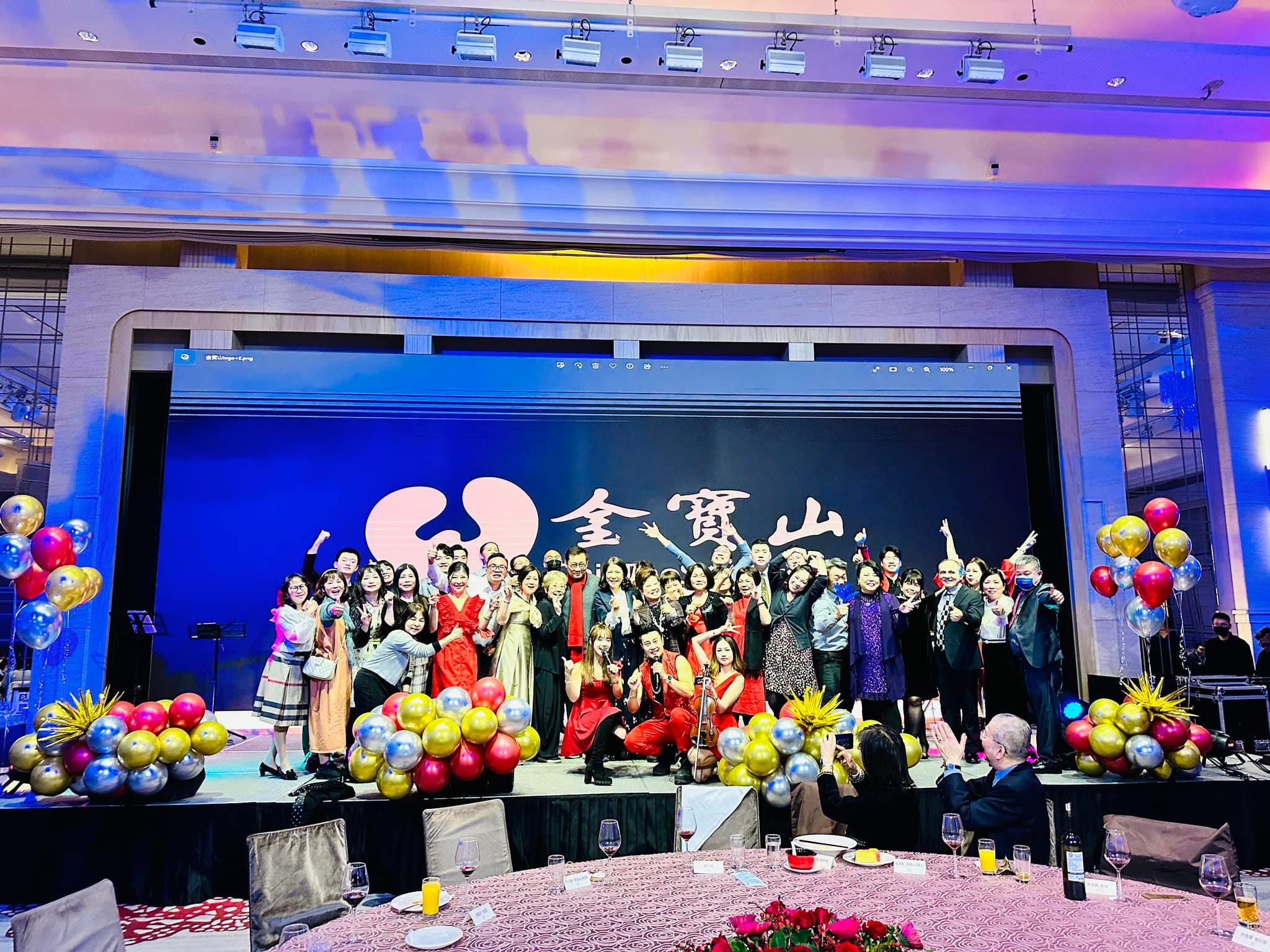 尾牙舞台上的大合照，舞台兩側是金色、紅色、藍色氣球堆