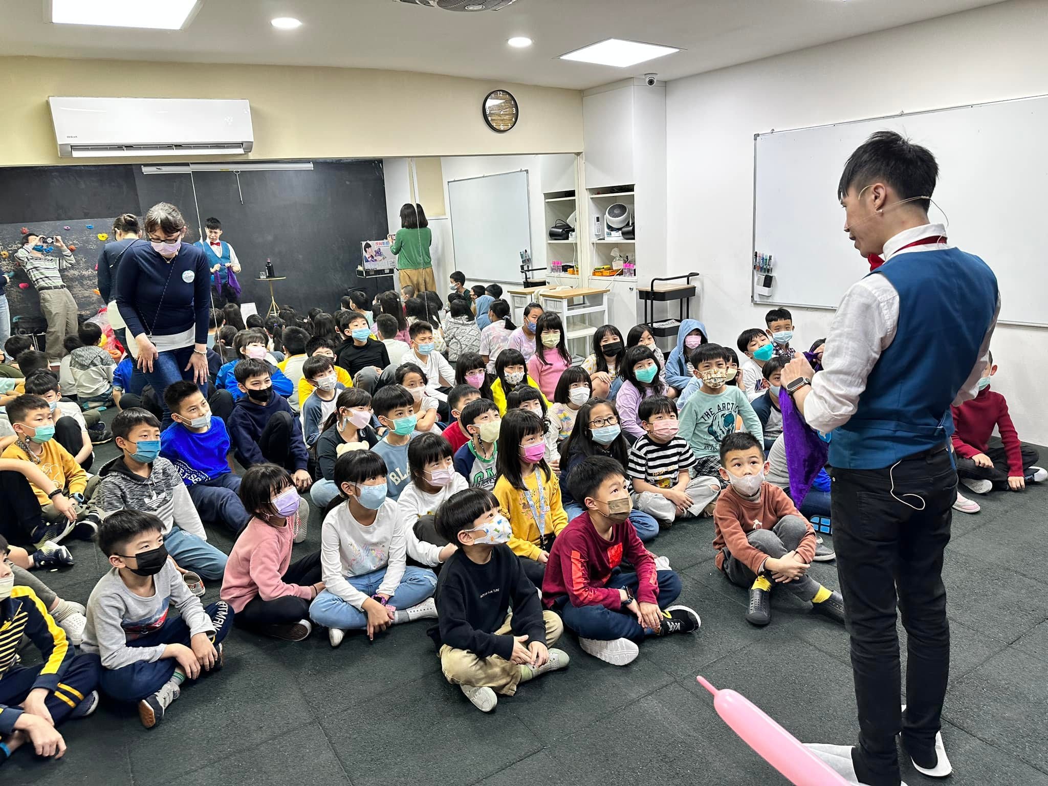 安親班教室裡，國小學童席地而坐，專心看柯男變魔術