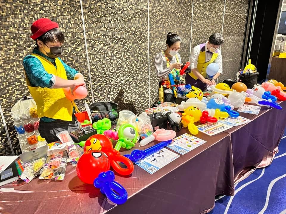 長桌上擺滿蜘蛛人、大眼怪、皮卡丘等造型氣球，氣球達人正在製作
