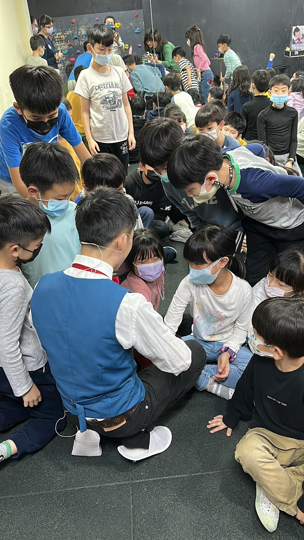 一群孩子圍著蹲在地上的柯男，近距離看魔術