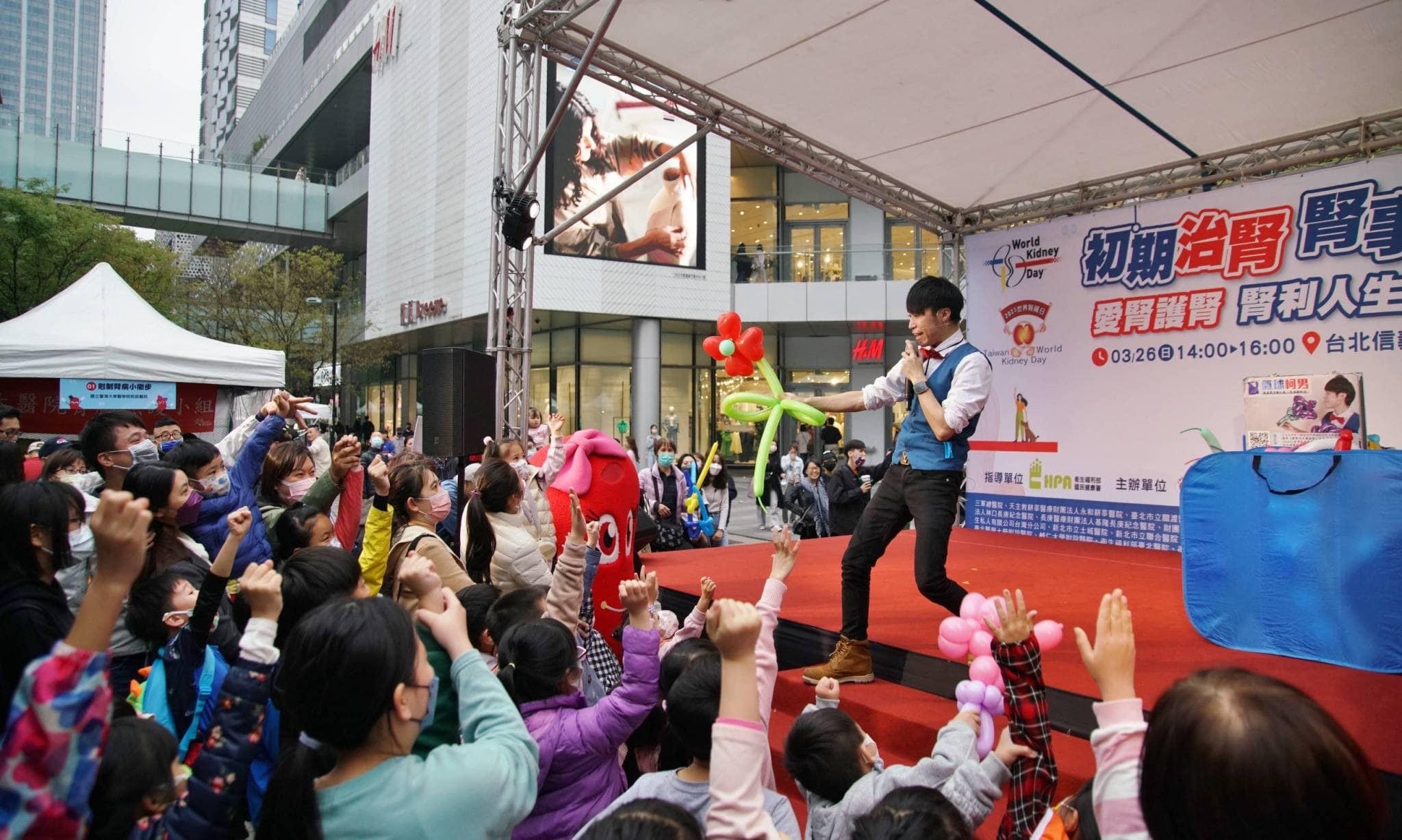 台北信義區戶外舞台上，柯男表演魔術，台前孩子們舉手搶著互動