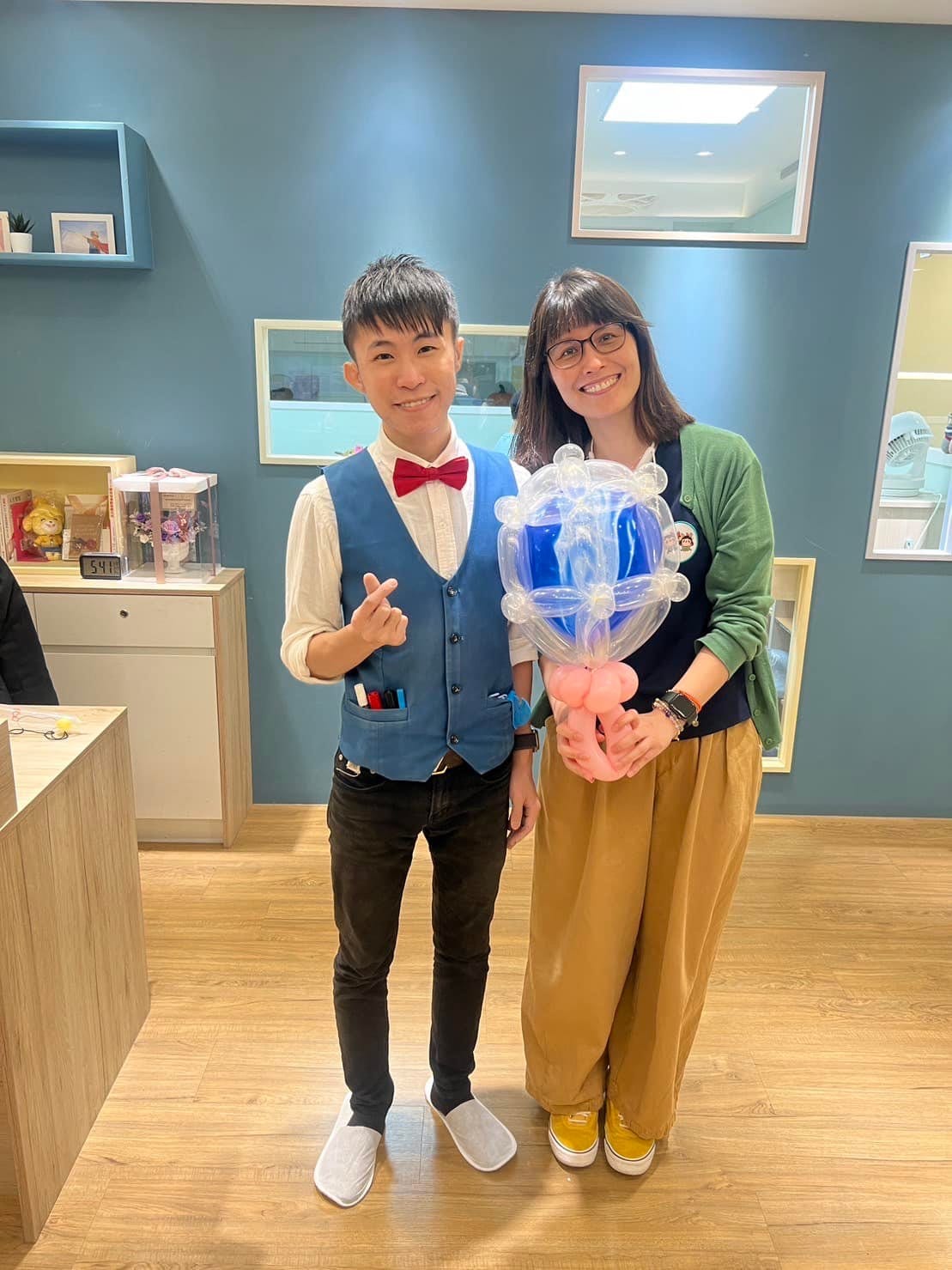 安親班老師捧著藍色大鑽石氣球，與柯男在接待區合照