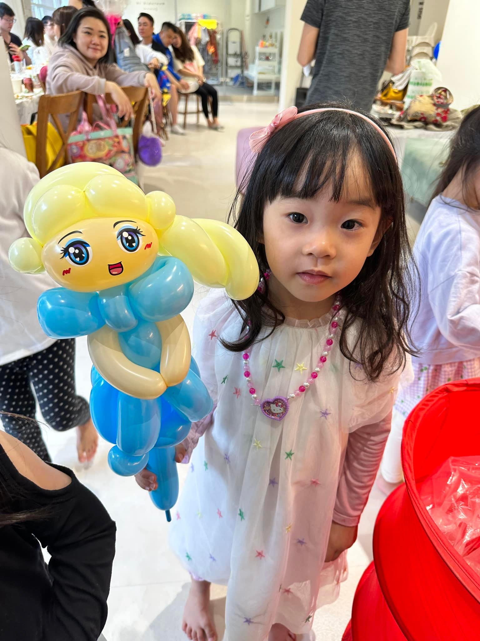 小女孩拿著冰雪奇緣艾莎公主造型氣球，金髮配藍色洋裝