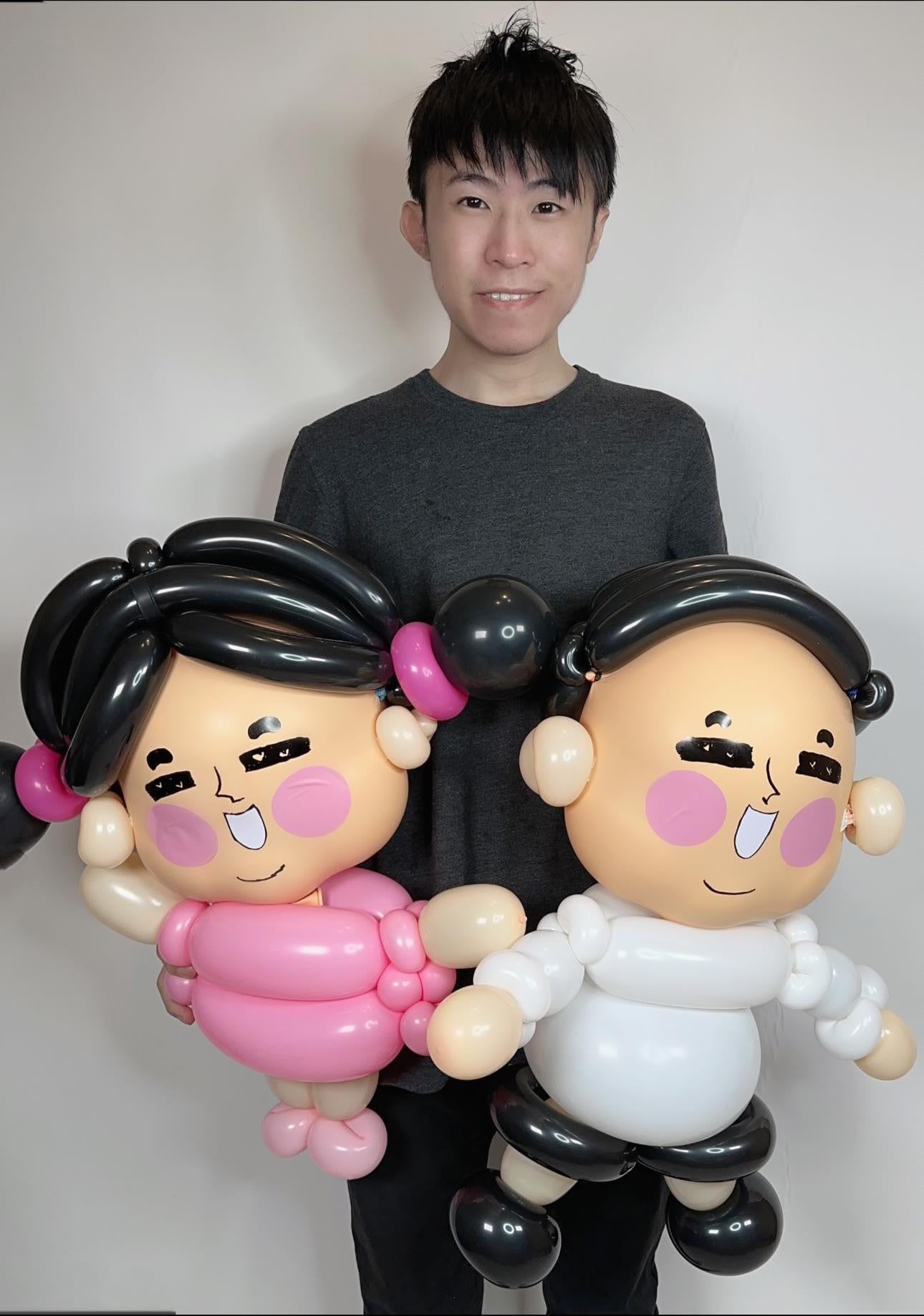 柯男抱著粉紅衣女生與白衣男生的達達與妃妃情侶氣球人偶