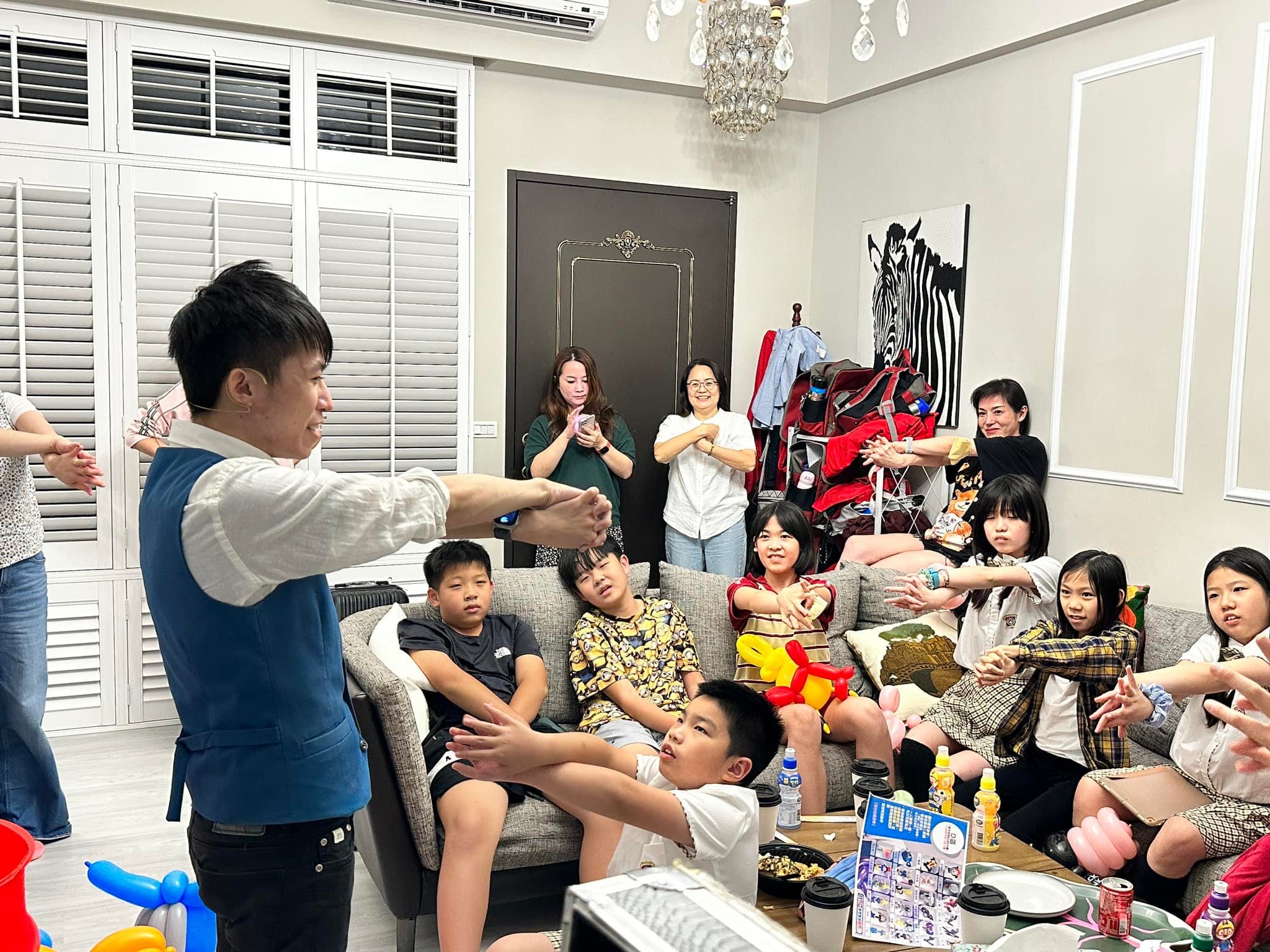 柯男在客廳對著沙發上的孩子們表演魔術