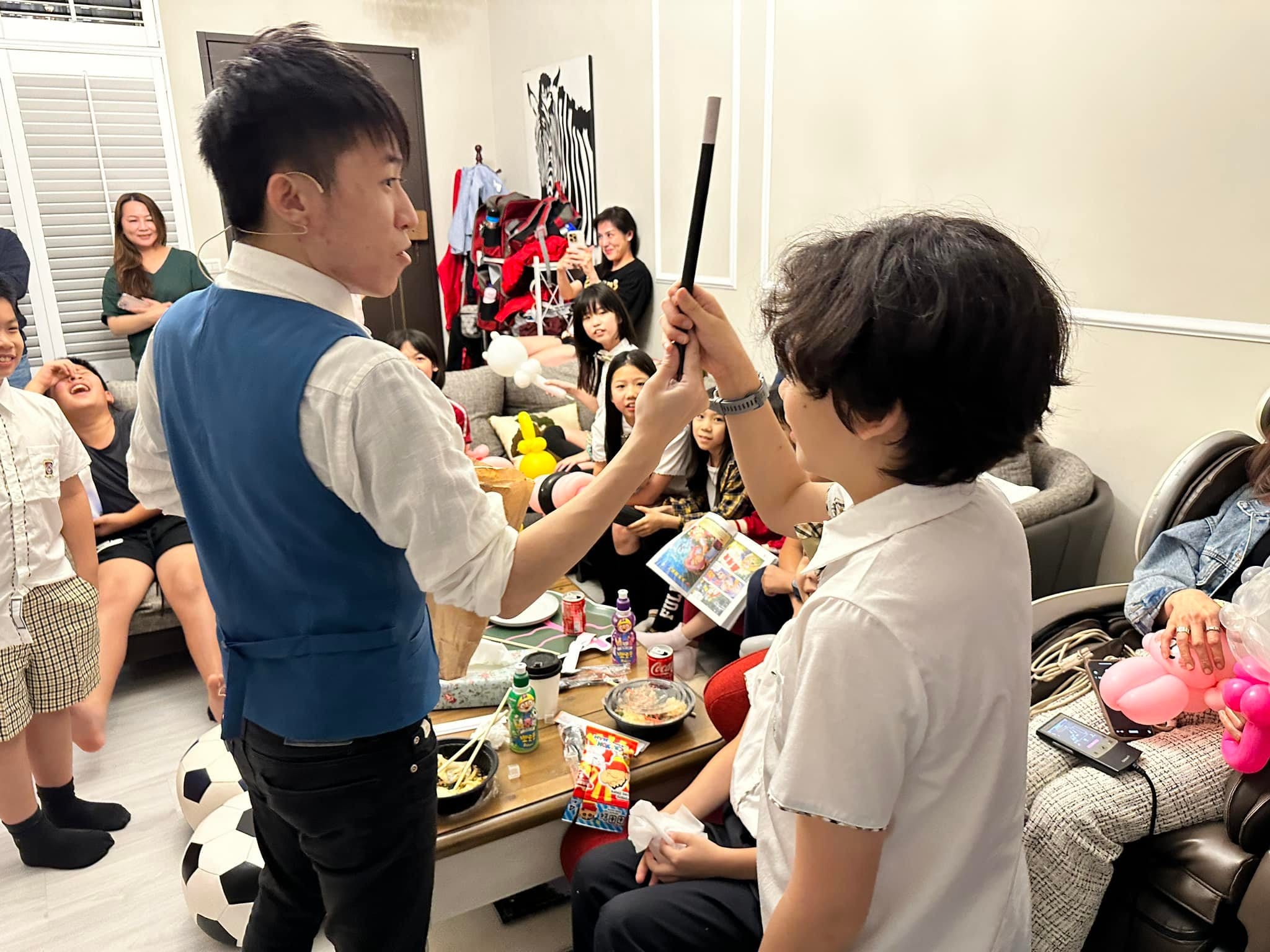 柯男拿著黑色魔術棒，請一位孩子上前幫忙