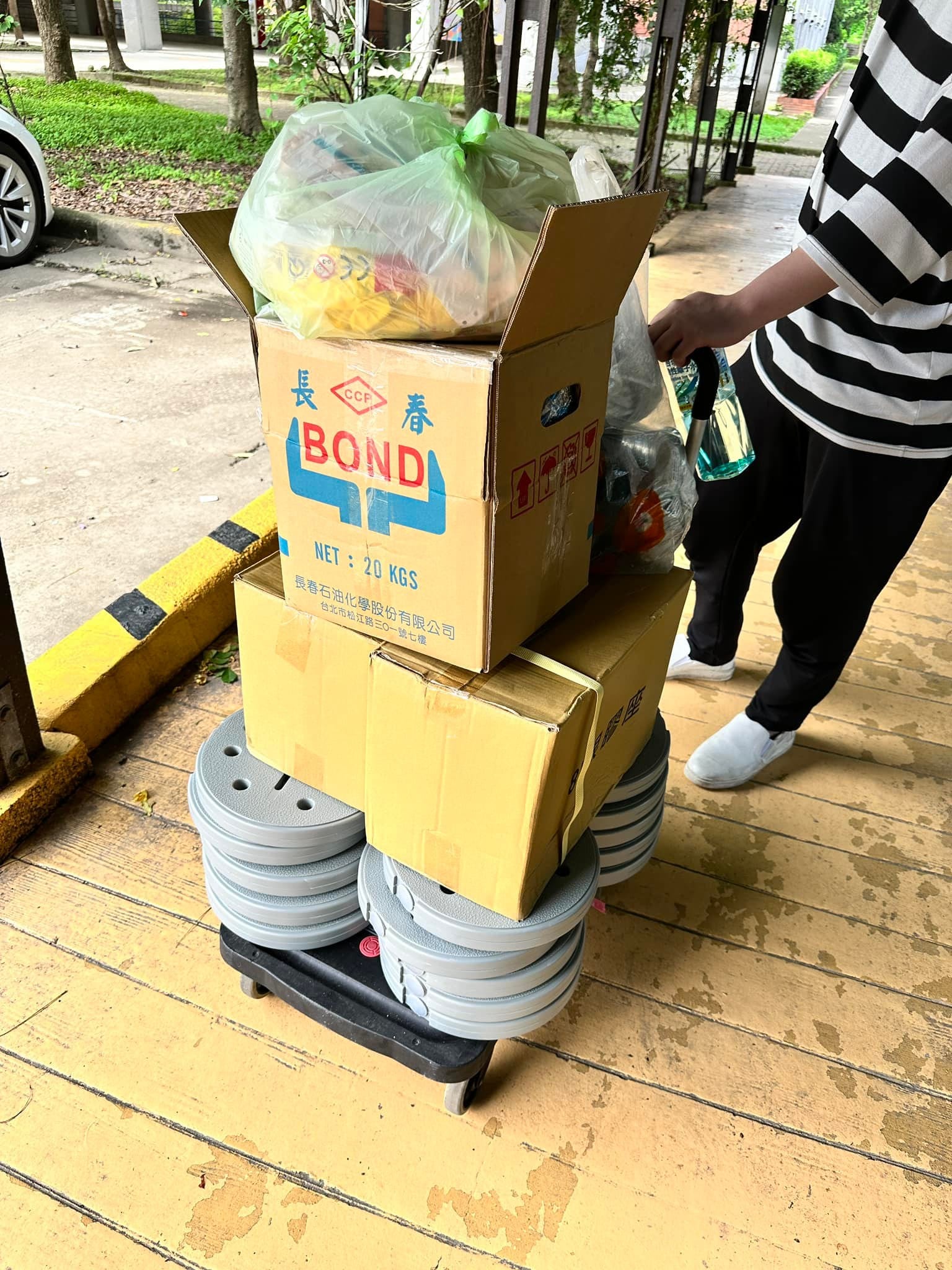 推車上疊滿灰色氣球柱底座與氣球材料紙箱，準備推進會場