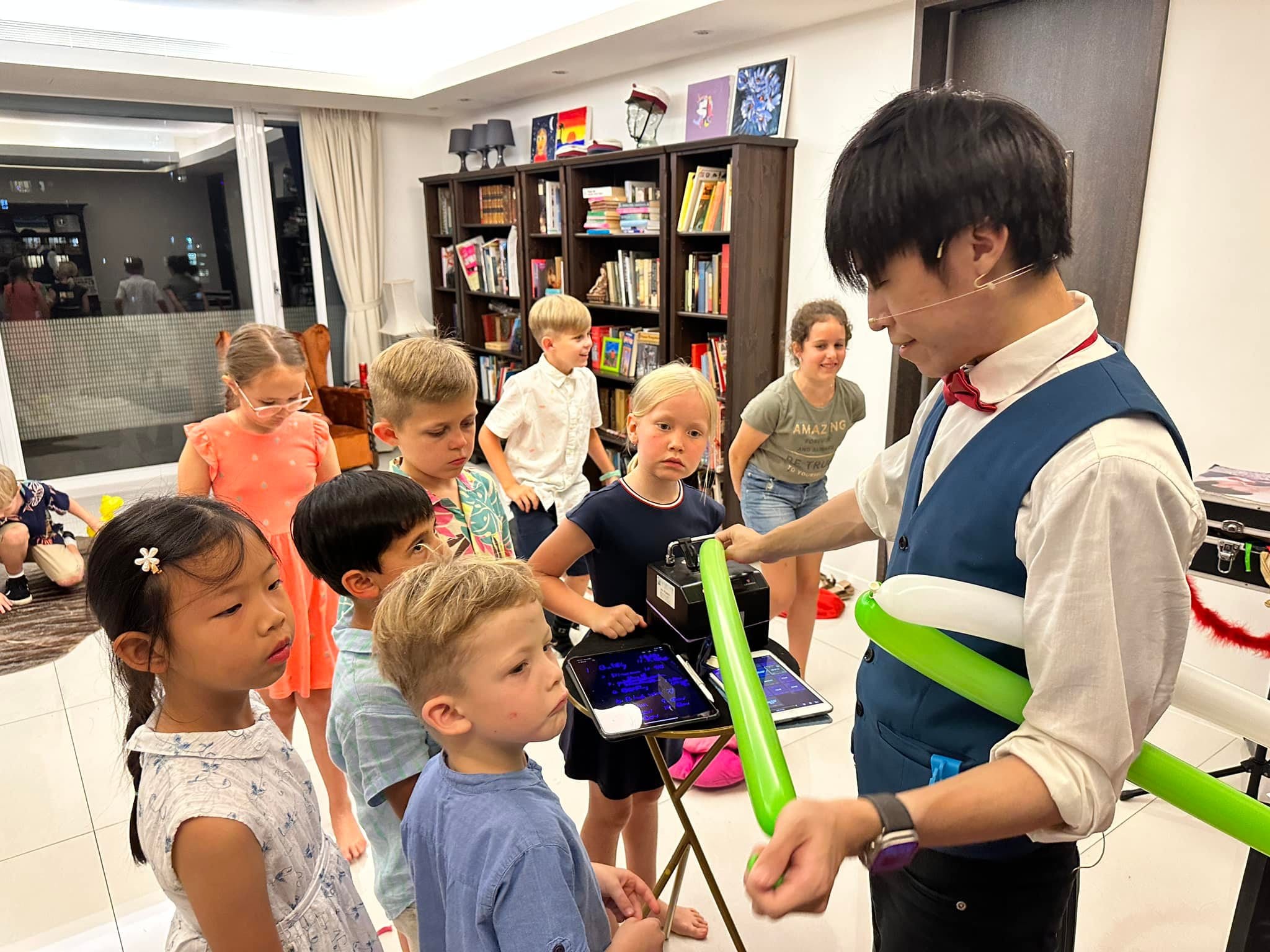 孩子們圍著平板挑選造型,柯男拿著綠色長條氣球準備折