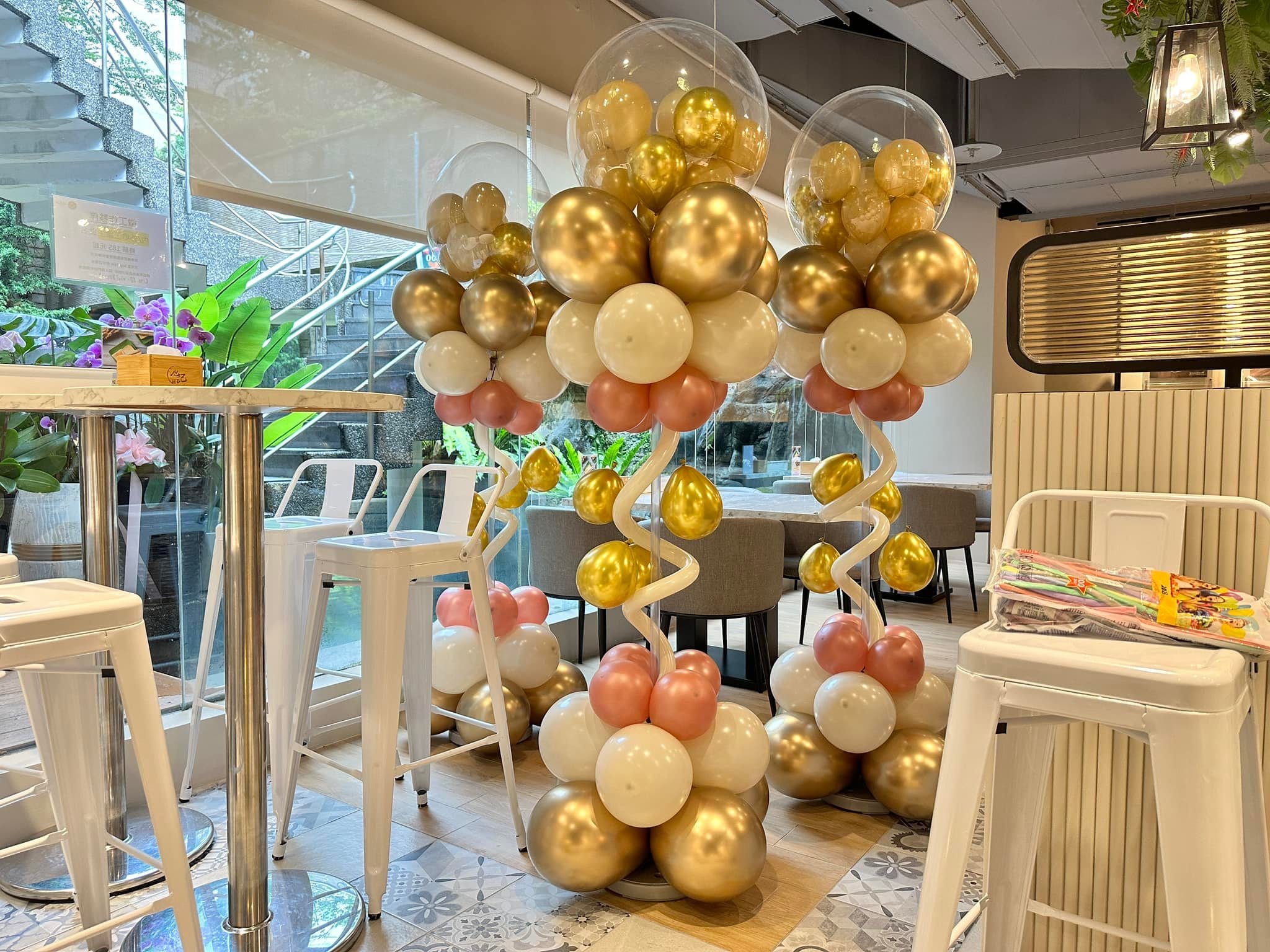 店內的金白粉色氣球柱，頂端是裝滿金色小氣球的透明波波球