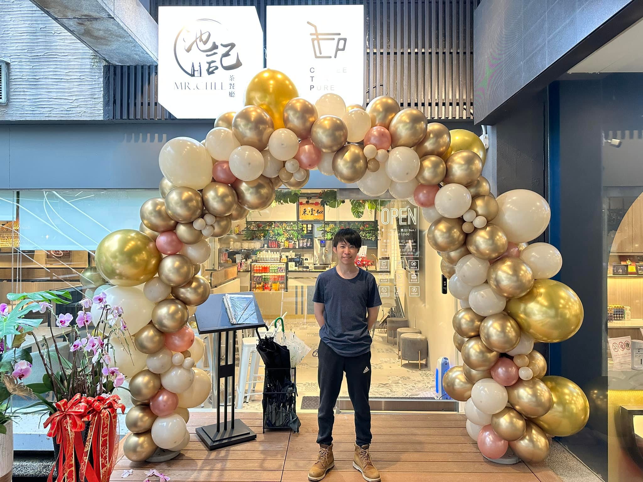 2023 年 6 月店家開幕，店門口的金白粉色不規則氣球拱門