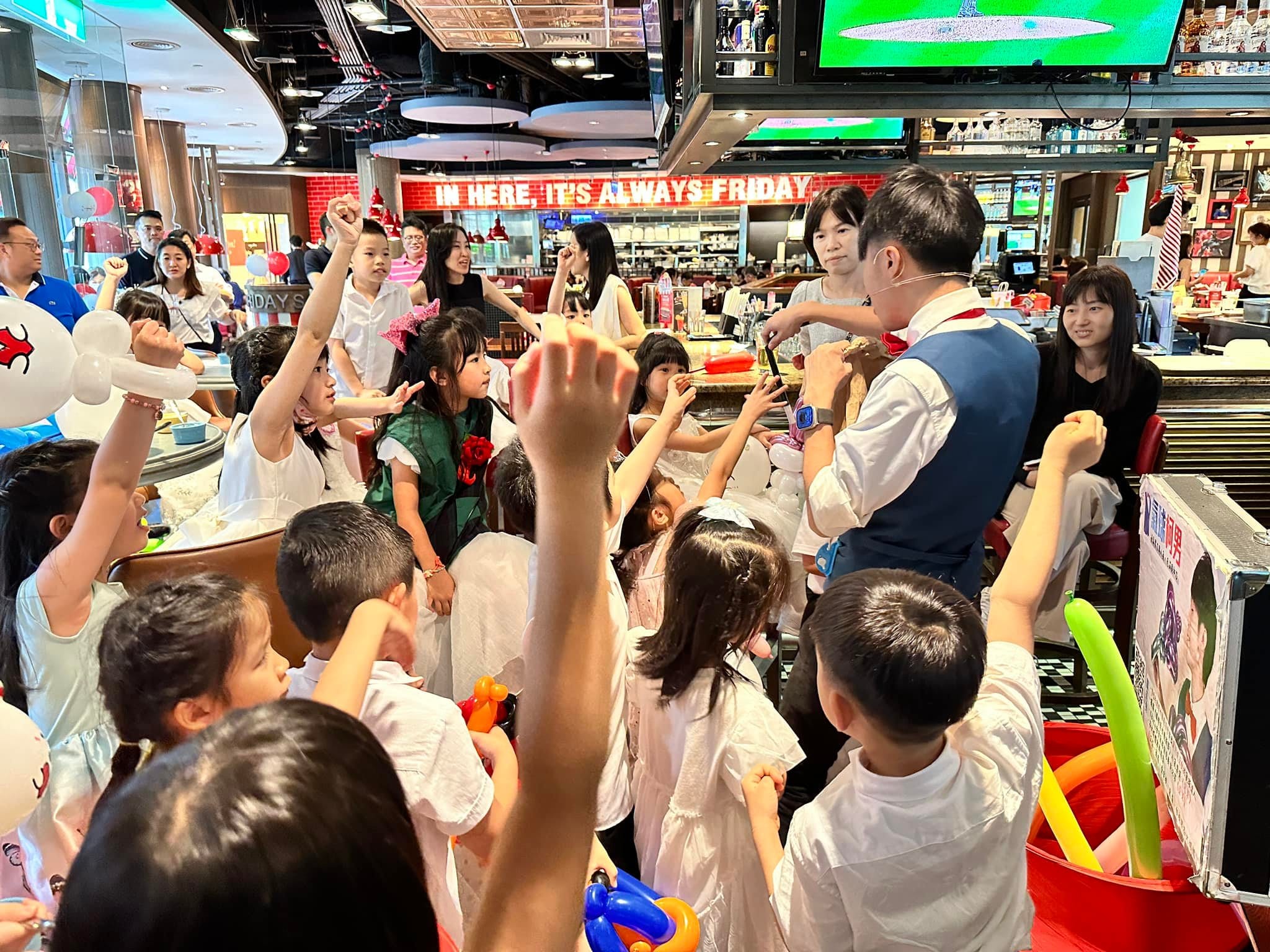 餐廳吧台前，孩子們圍著柯男高舉雙手搶著參與魔術