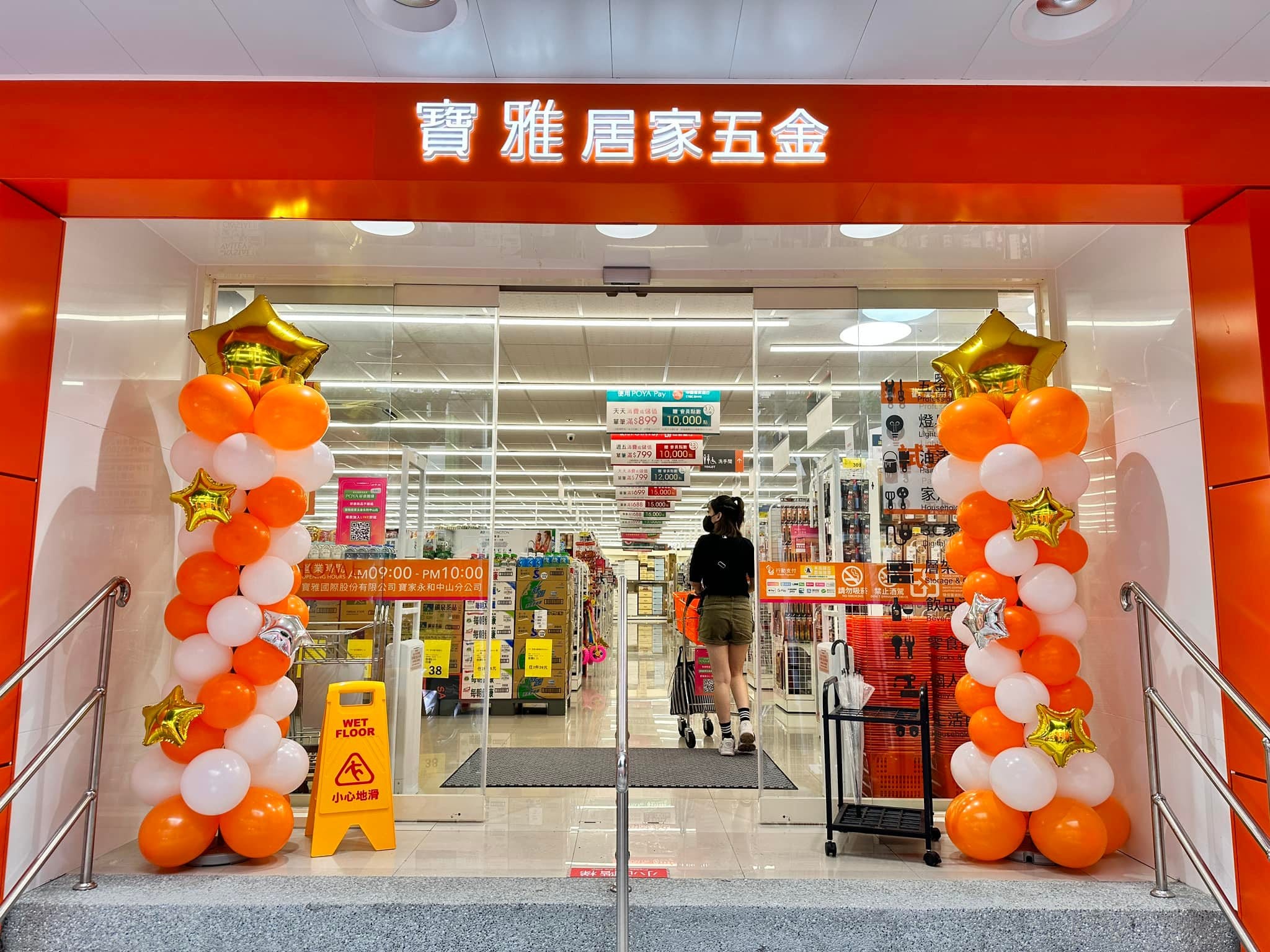 店門口兩側的橘白色氣球柱，柱上點綴金色星星鋁箔氣球