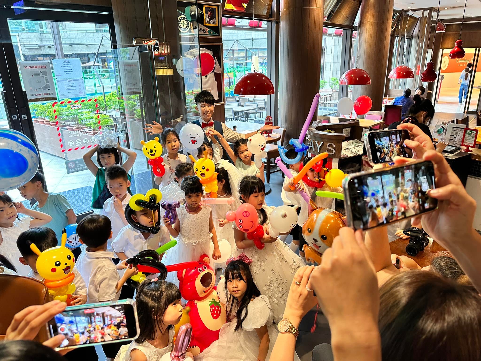 餐廳兒童派對，孩子們高舉皮卡丘、草莓熊等造型氣球，家長舉手機拍照