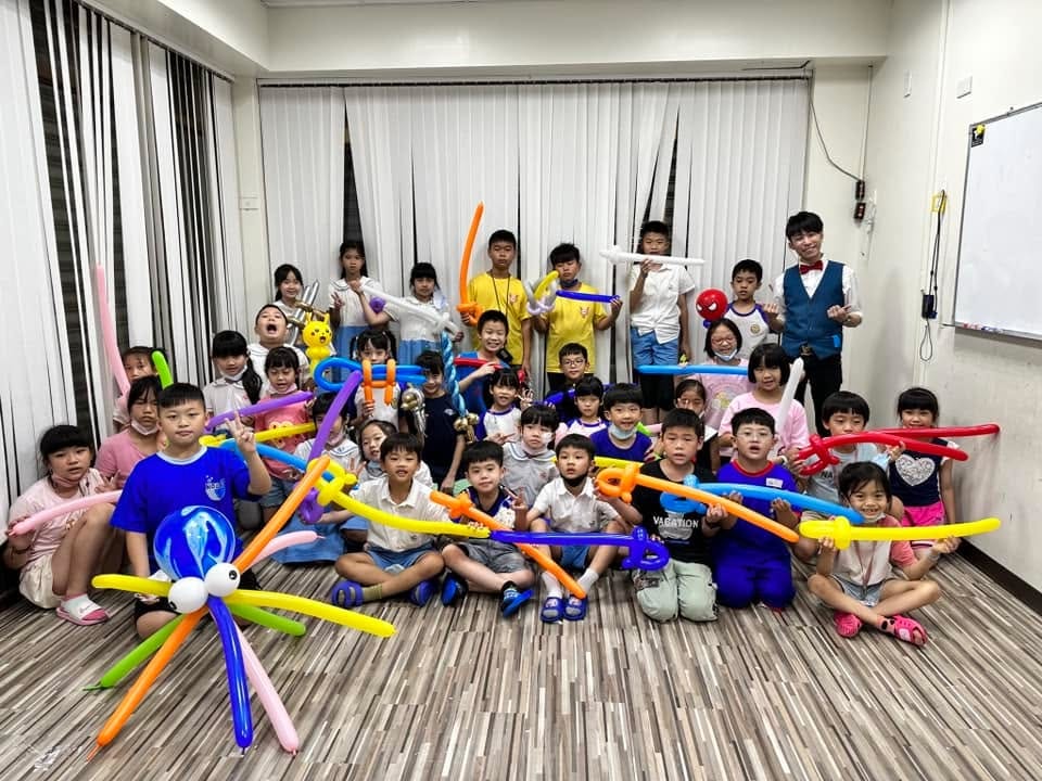 安親班孩子們拿著寶劍、章魚等造型氣球，和柯男在教室裡大合照