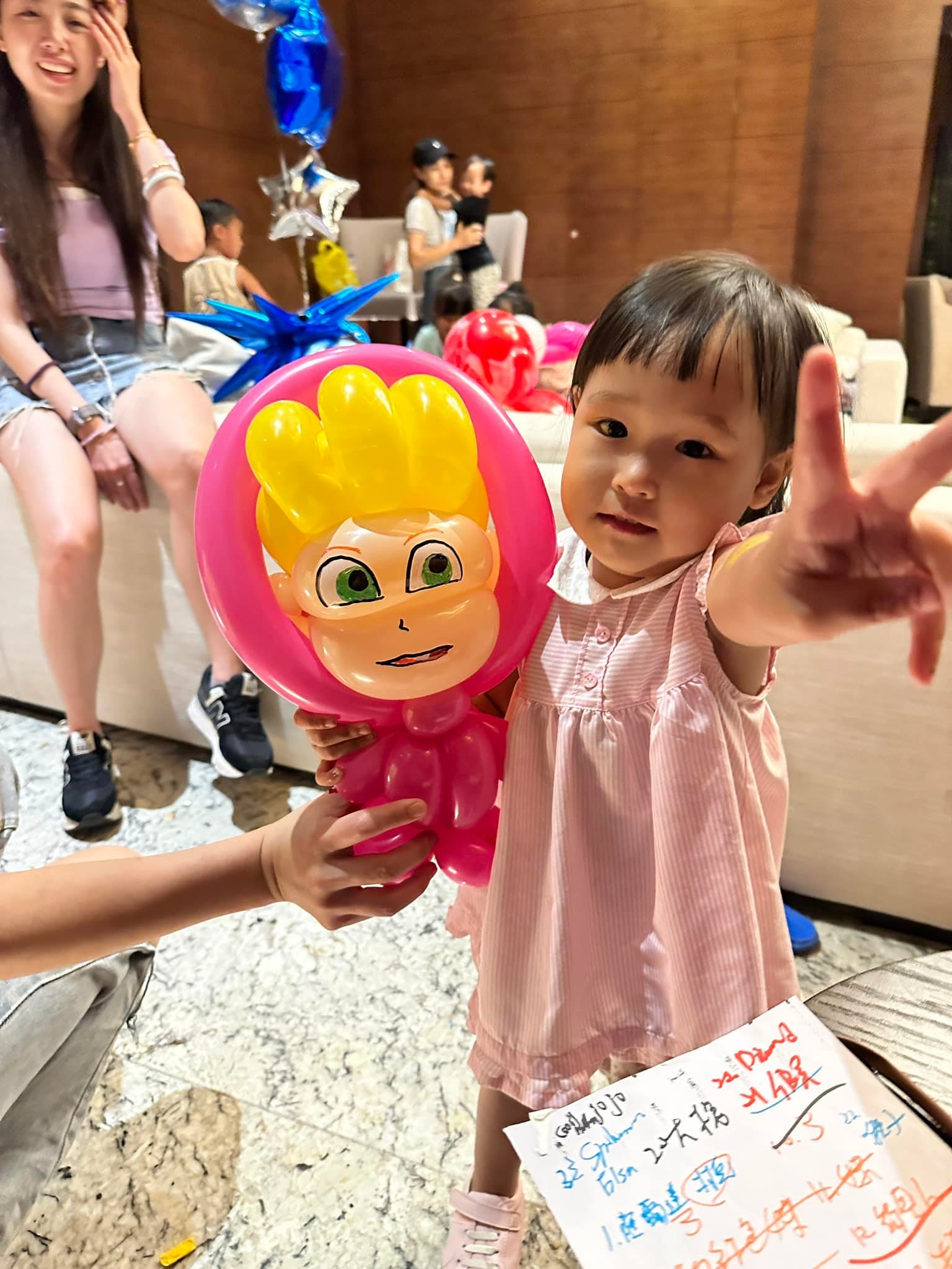 小女孩比 YA,旁邊是粉紅頭巾、黃色頭髮的娃娃造型氣球
