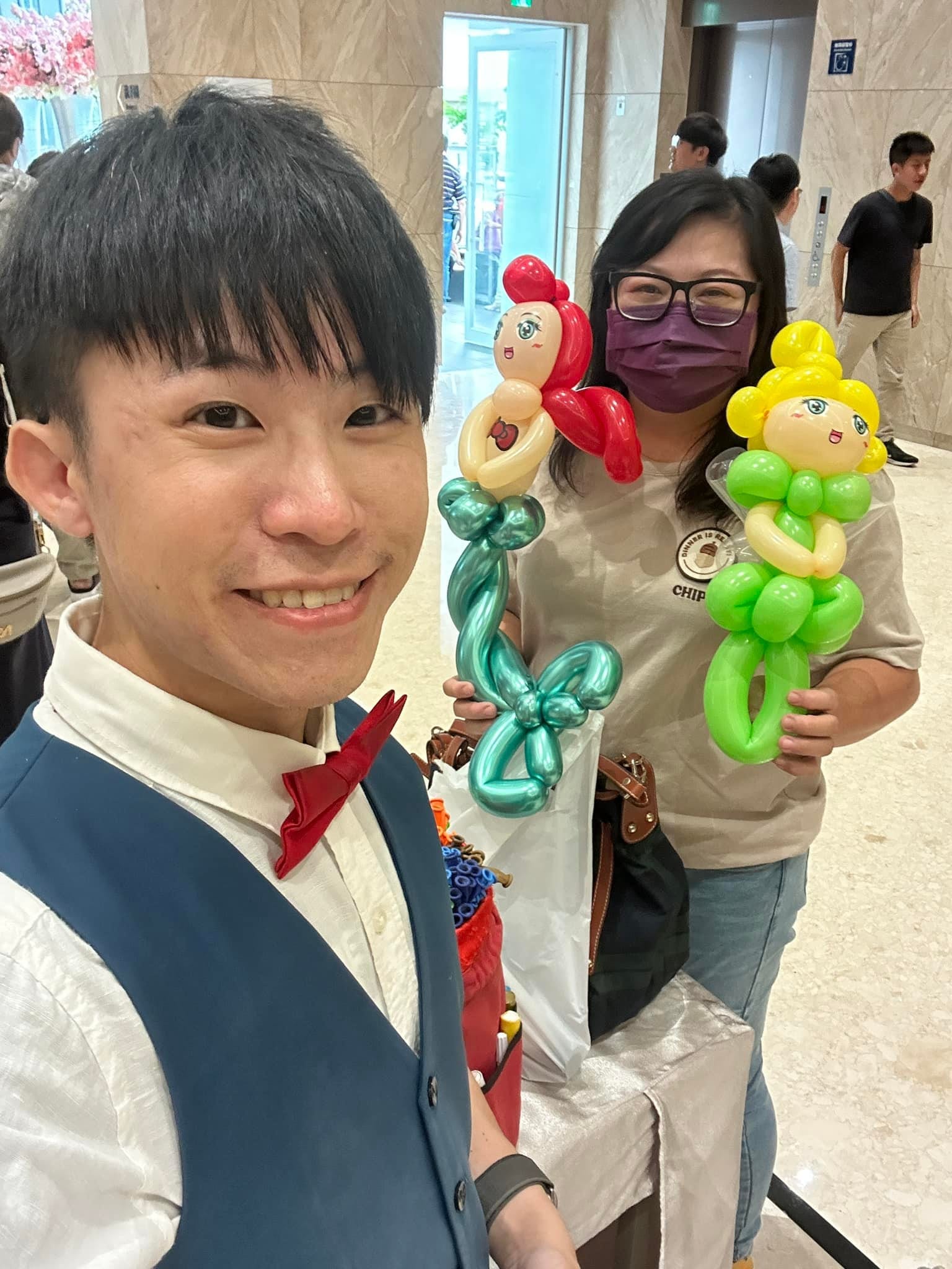 婚禮賓客拿著紅髮魚尾與黃髮綠裙的娃娃造型氣球，和柯男合照