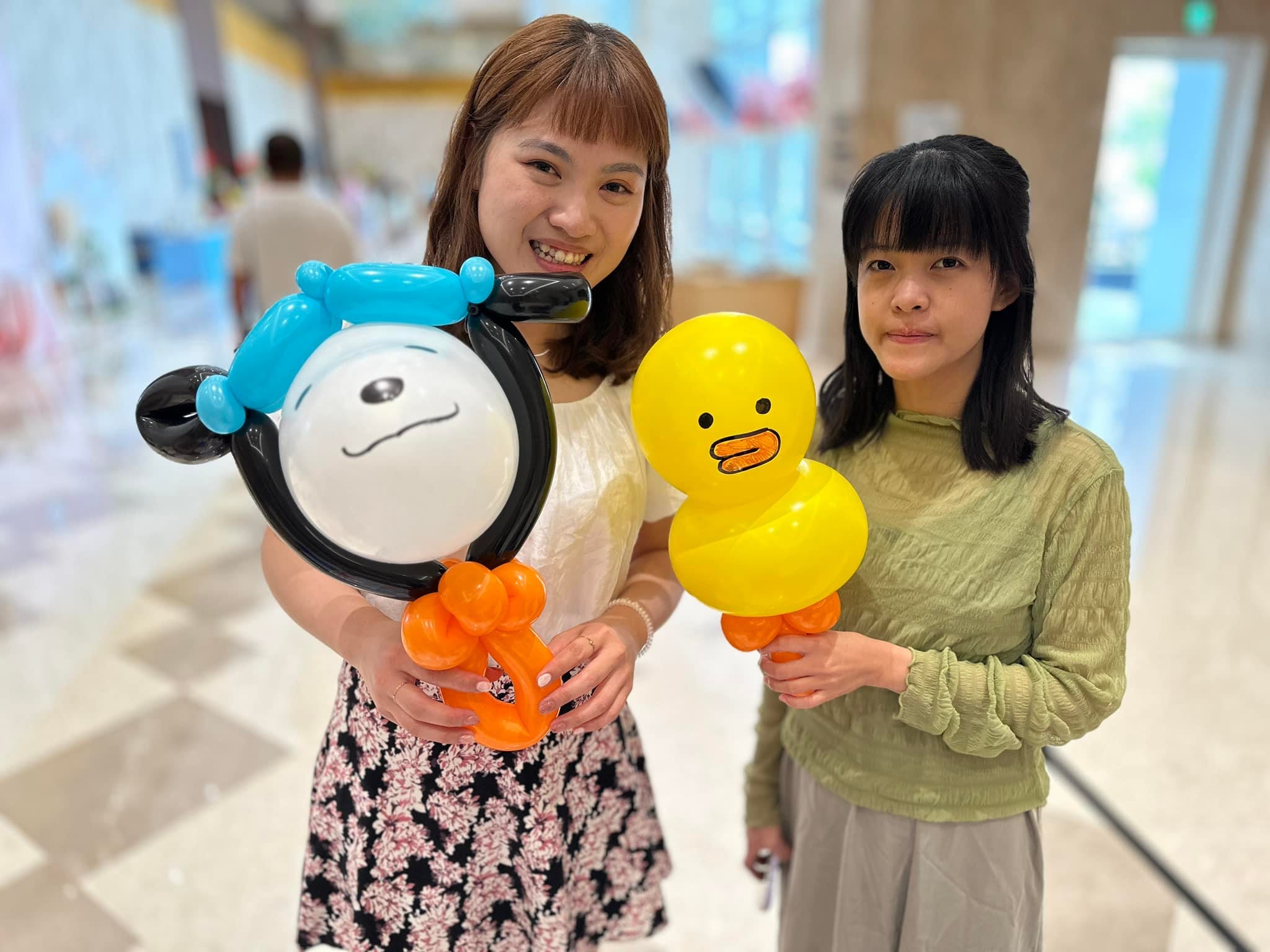 兩位女賓客分別拿著白色小狗與黃色小鴨造型氣球