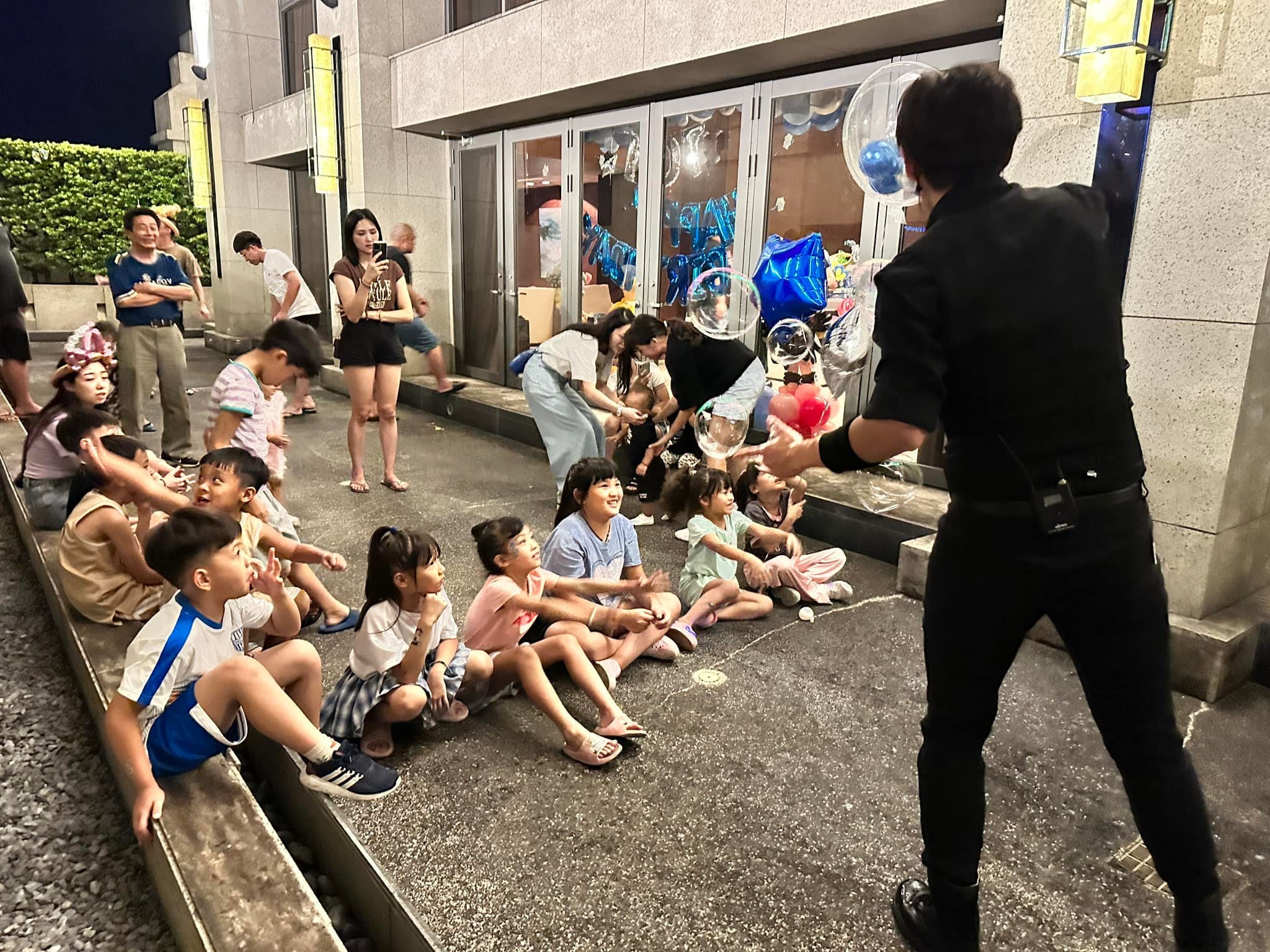 夜晚的戶外泡泡秀,孩子們坐在台階上看表演者吹出大泡泡