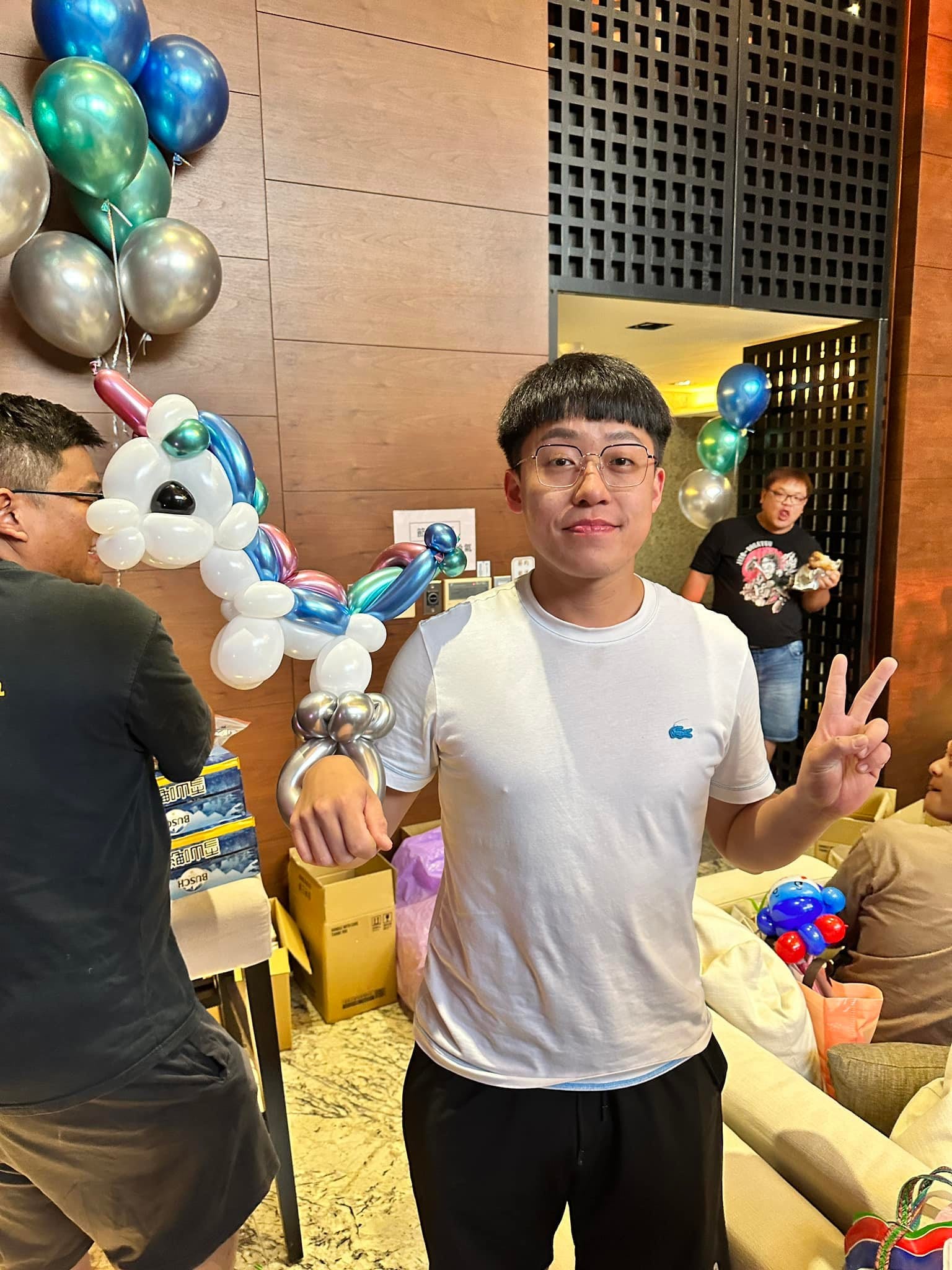 男生拿著彩虹鬃毛的白色小馬造型氣球比 YA