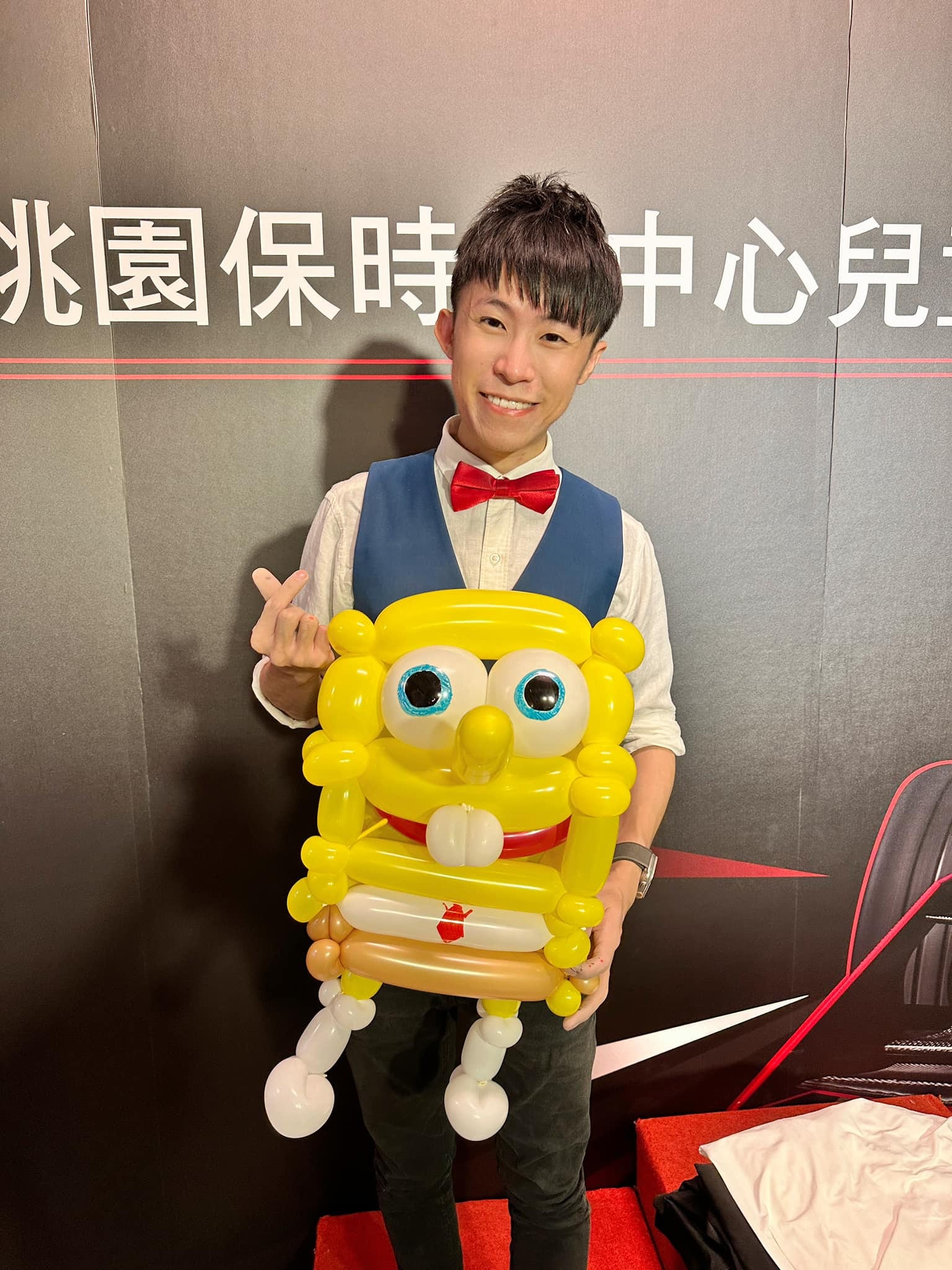柯男在桃園保時捷中心兒童卡丁車背板前，捧著立體海綿寶寶造型氣球