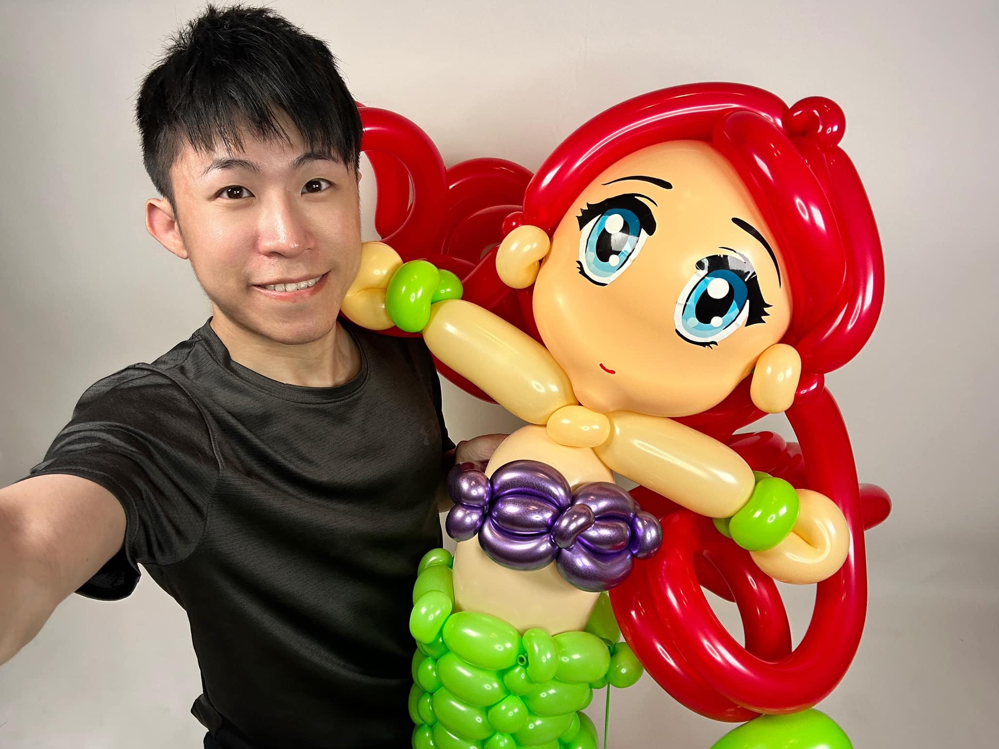 柯男自拍，身旁是比上半身還大的小美人魚氣球人偶