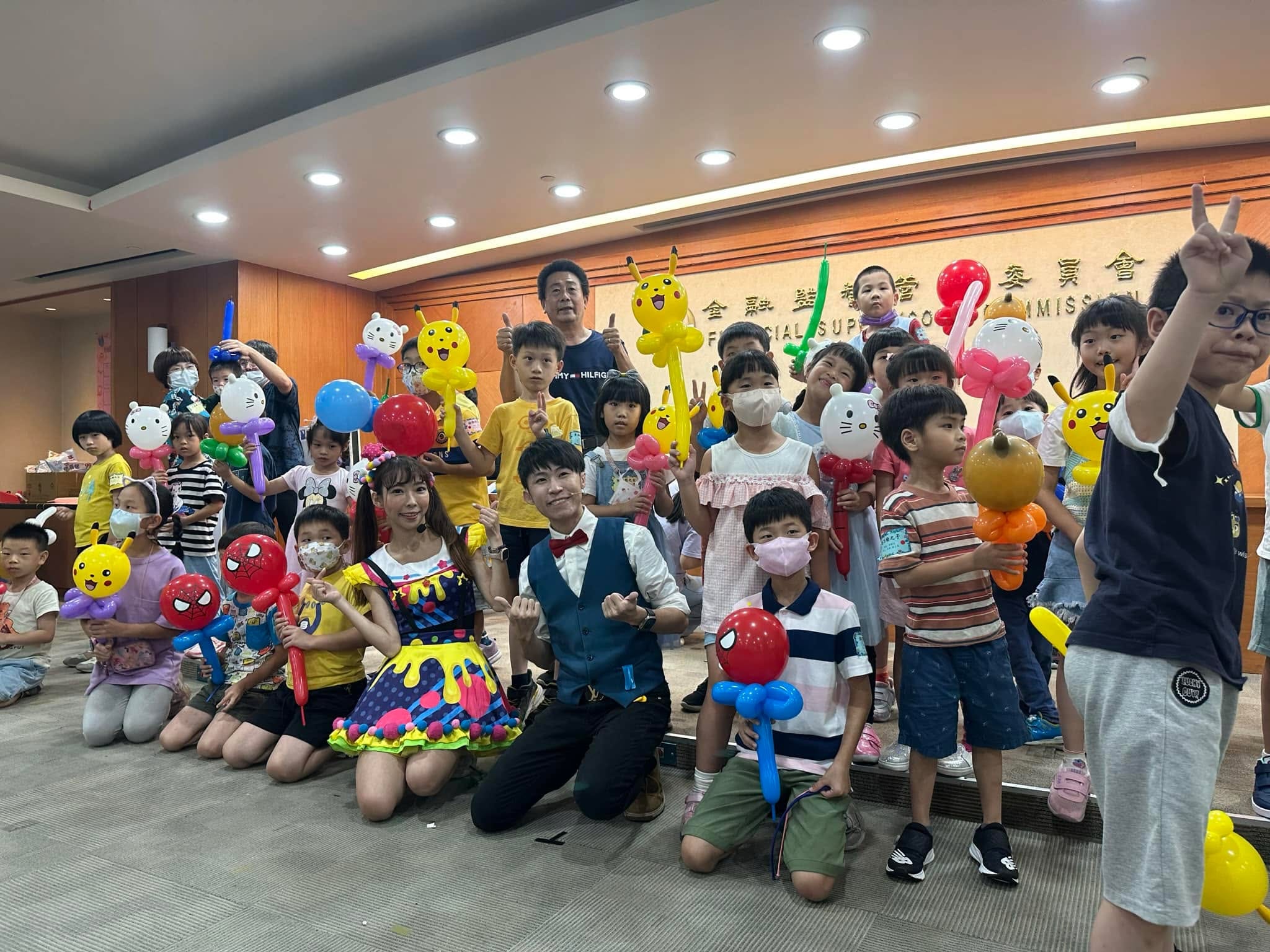 新北板橋金管會親子日，孩子們拿著皮卡丘、Hello Kitty 等造型氣球和柯男大合照