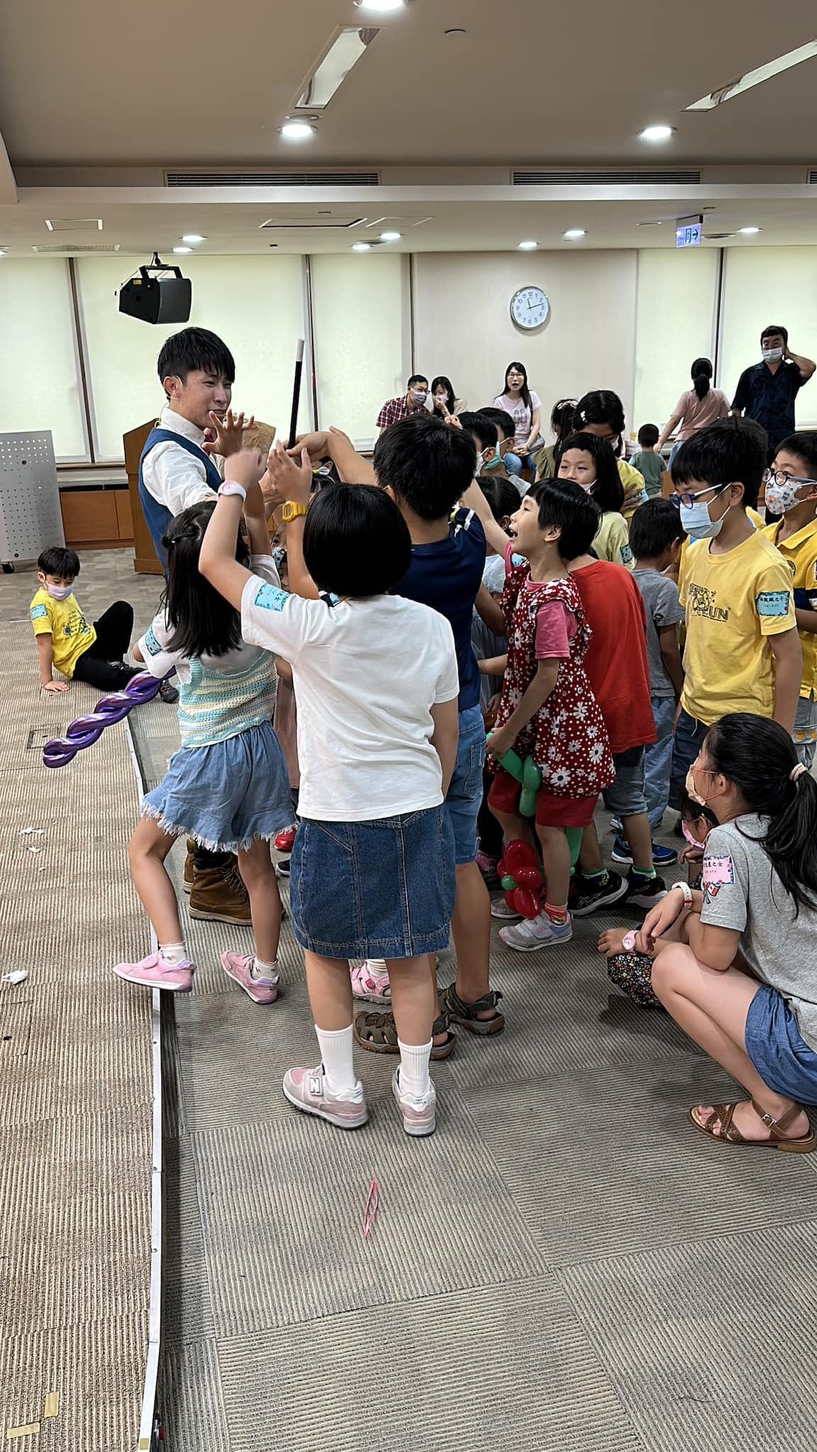 孩子們圍著柯男踮腳伸手，搶著參與魔術互動