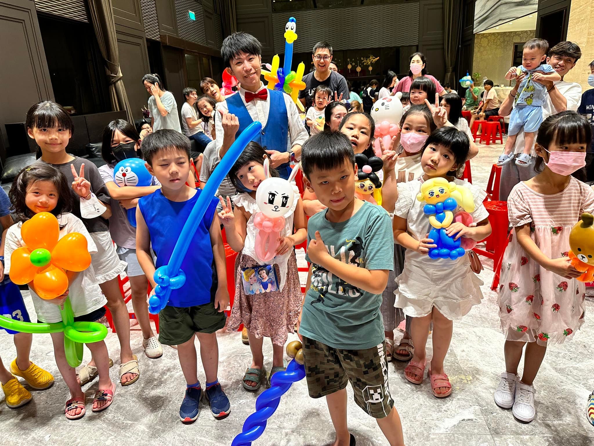 孩子們拿著花朵、寶劍、小兔與小熊造型氣球，和柯男一起比讚合照
