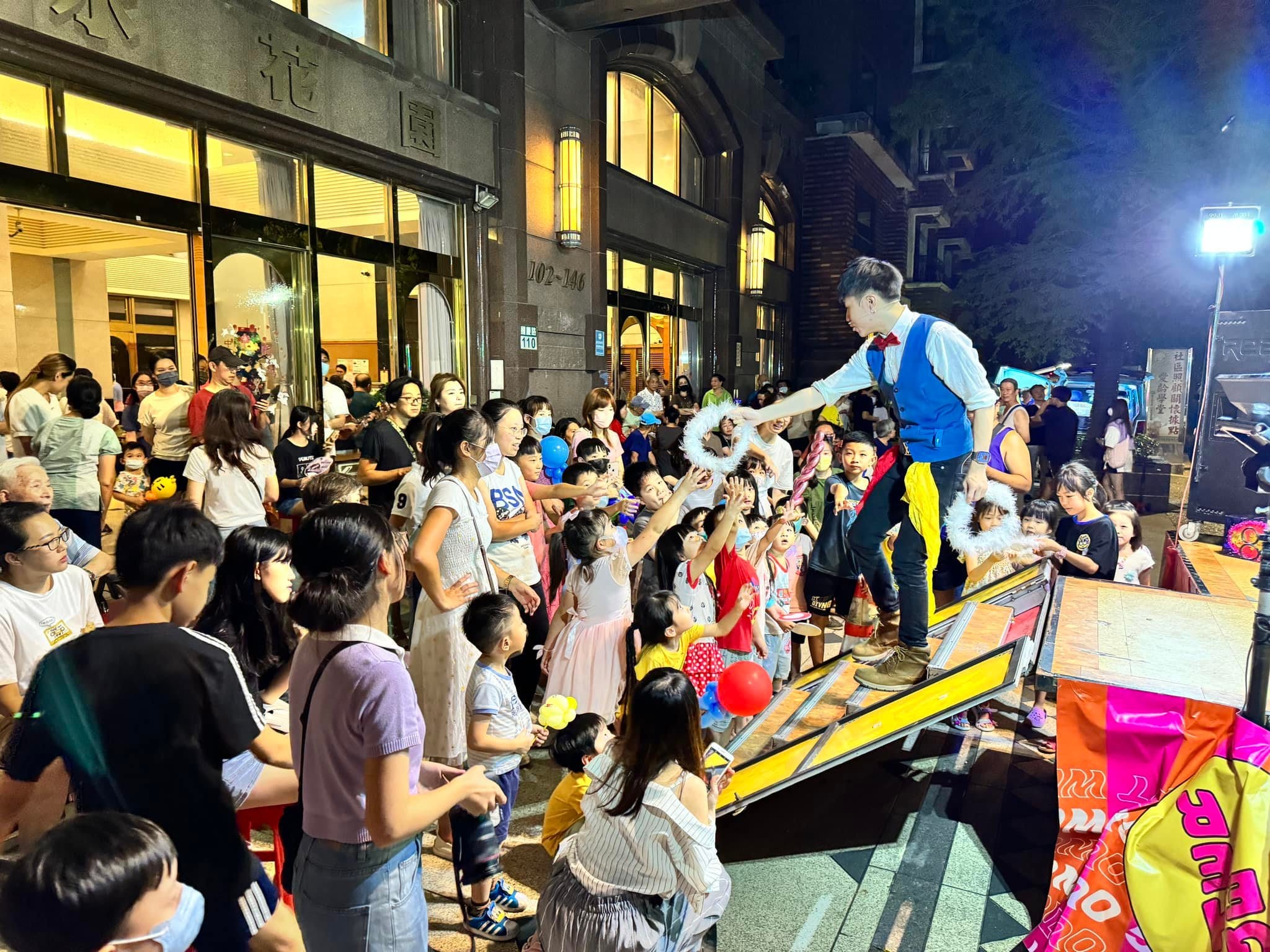 柯男站在戶外黃色舞台邊緣,台前大批孩子舉手搶著當助手