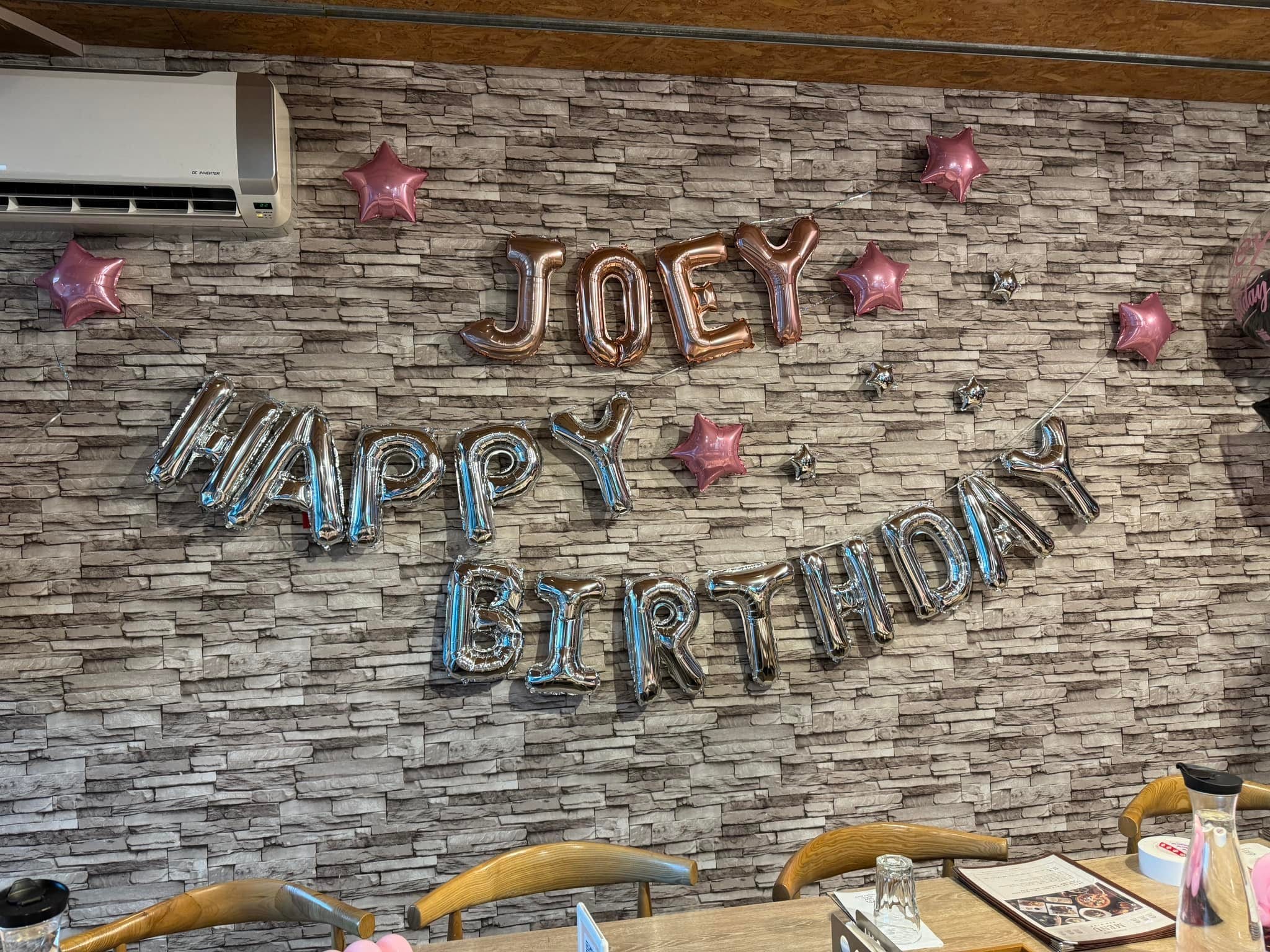 文化石牆上的玫瑰金名字字母與銀色 HAPPY BIRTHDAY 氣球