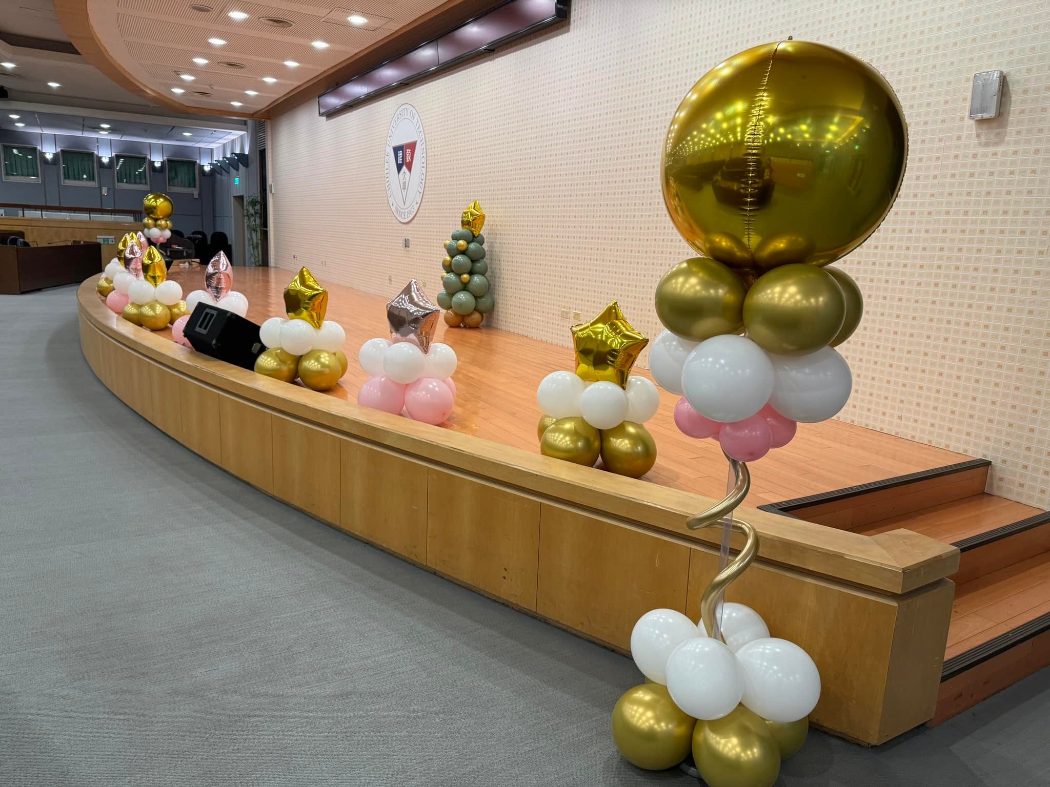 舞台邊緣擺著一排小型氣球擺飾，前方立著金色圓球氣球柱