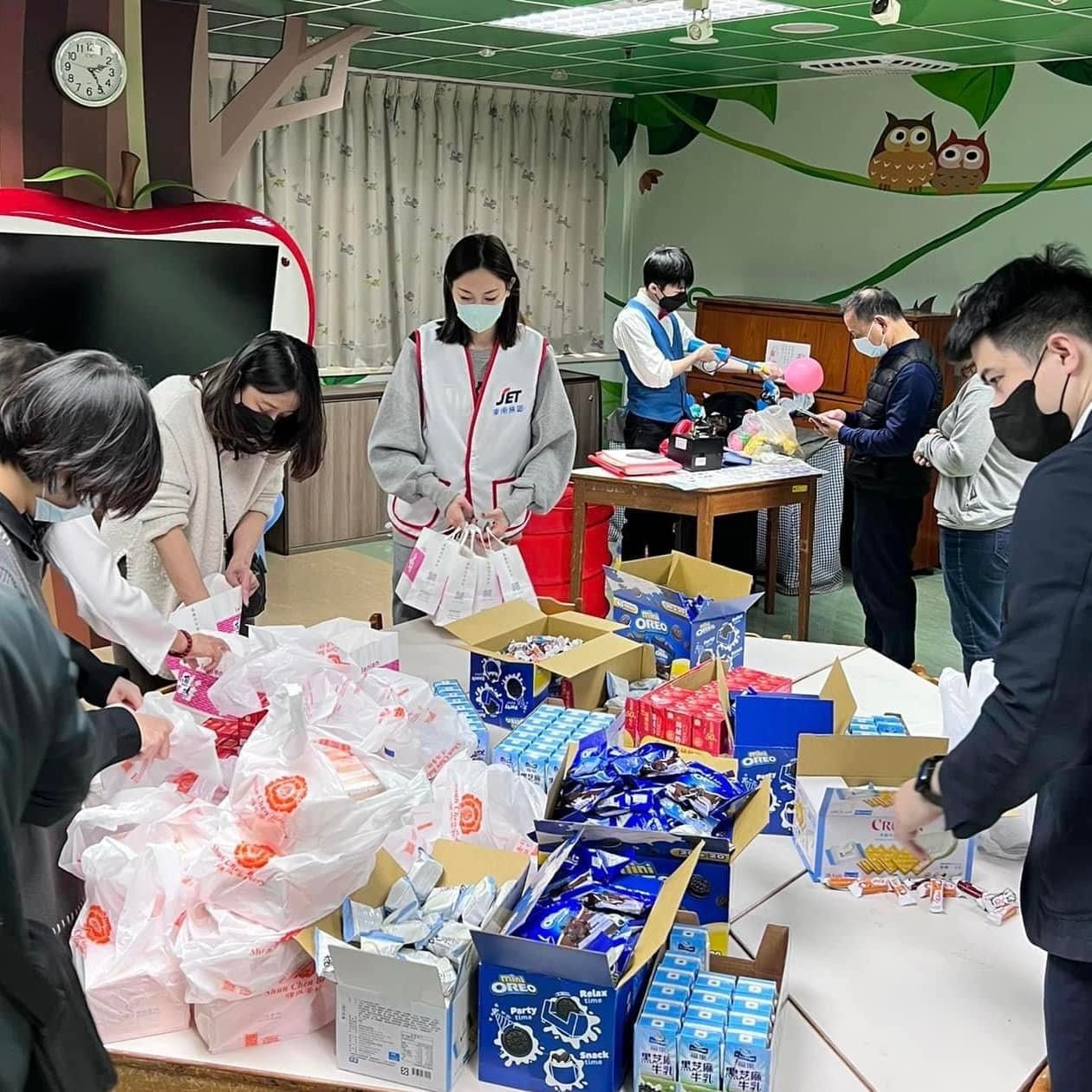 病房活動室裡，同仁們圍著長桌分裝餅乾牛奶等小禮物