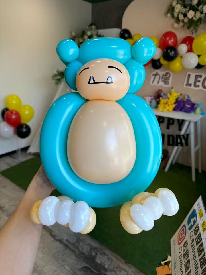 藍綠色卡比獸造型氣球特寫，後方是生日派對背板